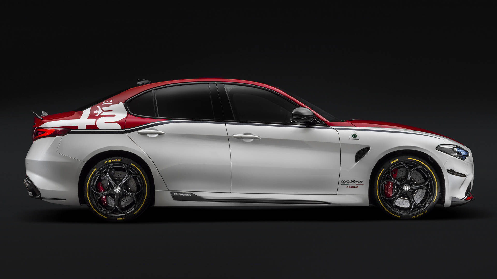 alfa romeo iPhone 桌布 壁紙 — 一輛時尚的銀色阿爾法羅密歐轎車，帶有紅色點綴和賽車貼紙，側面立於深色工作室背景前。