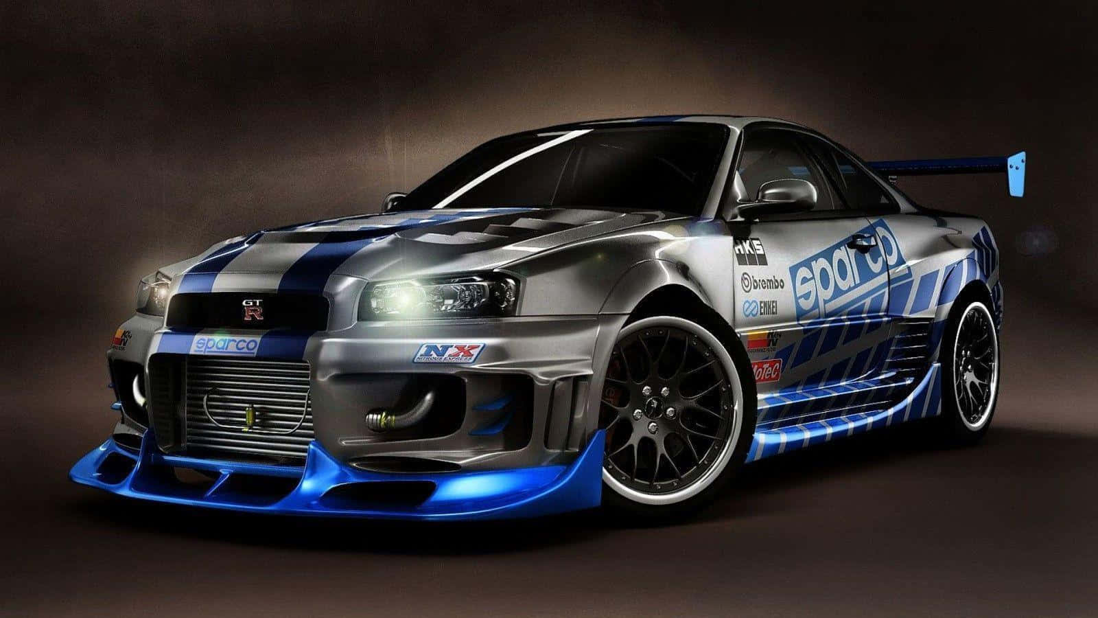 Paul Walker Skyline 桌布 壁紙 — 一輛時尚的銀藍色賽車，帶有贊助商貼紙和發光車頭燈，在黑暗的攝影棚中戲劇性地擺拍。