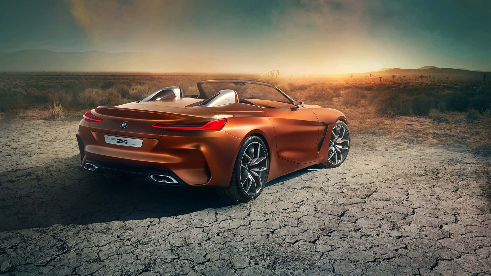 Bmw Z4 桌布 壁紙 — 一輛時尚的銅色BMW Z4敞篷跑車停泊在龜裂的沙漠地上，背景是金色的日落天空。