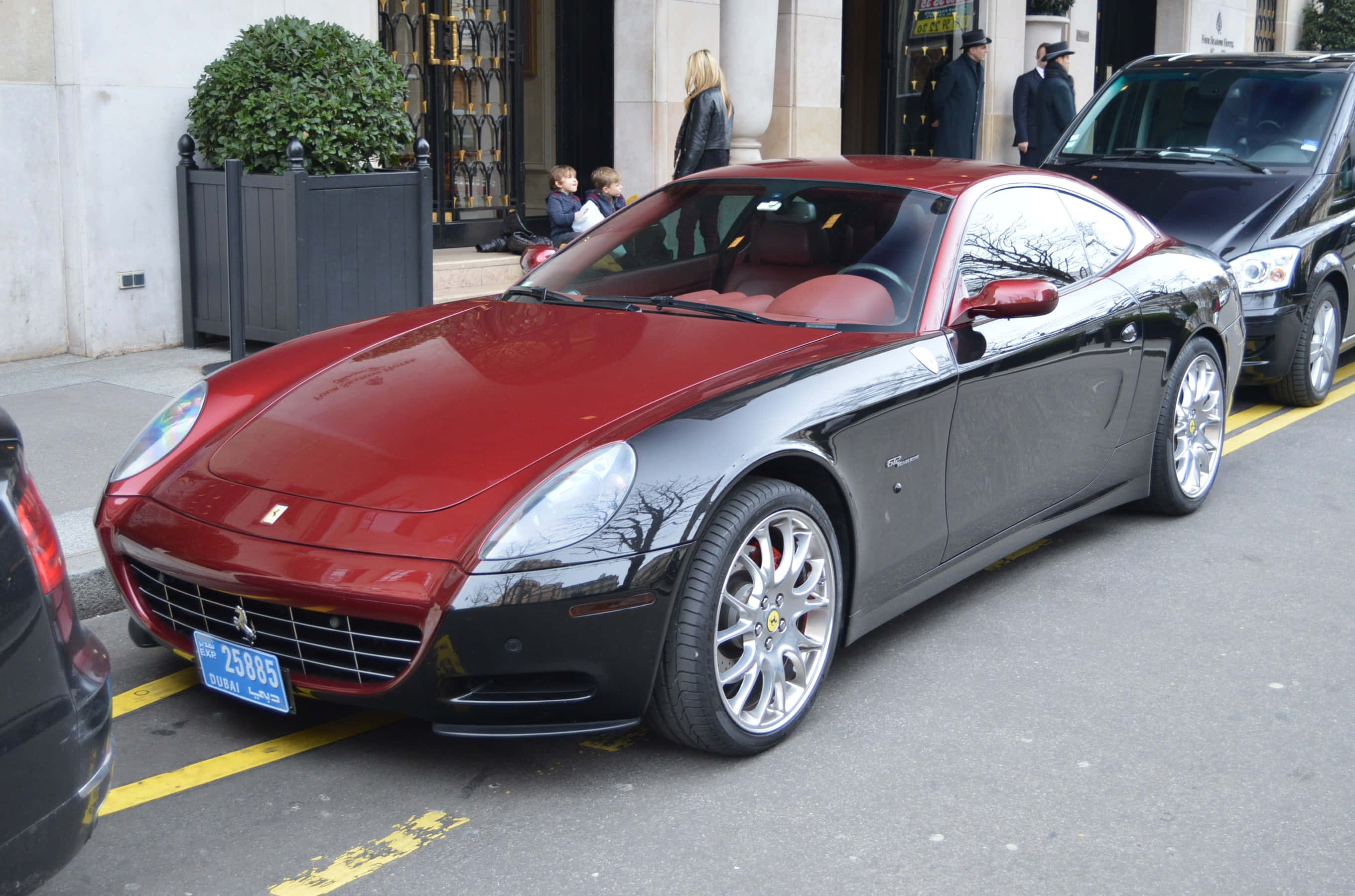 Ferrari 612 Scaglietti 桌布 壁紙 — 一輛時尚的雙色法拉利跑車停泊在城市的街道上，背景有行人和建築物。