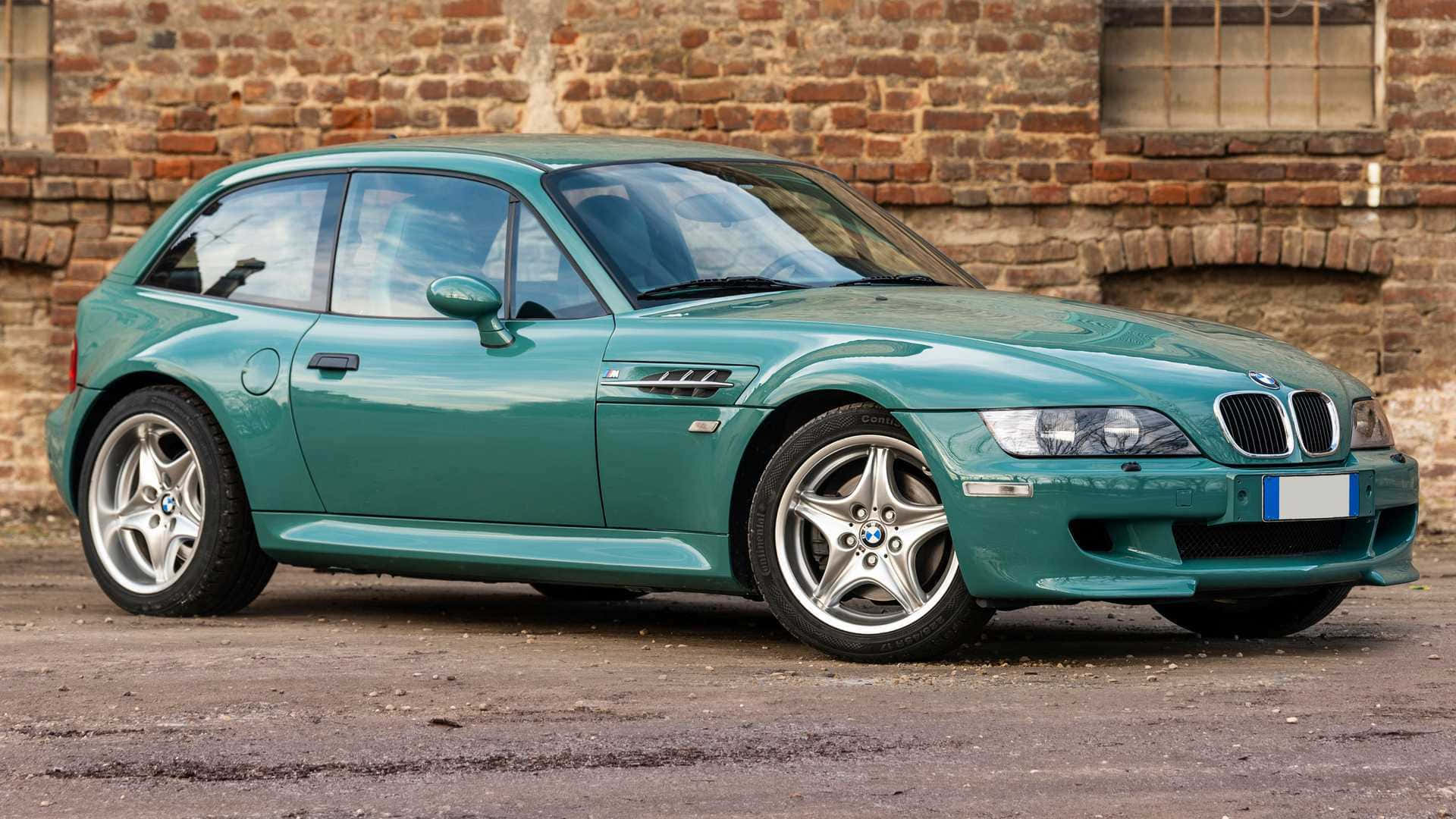 BMW 動圖 桌布 壁紙 — 一輛時尚的青綠色BMW Z3跑車停放在風化的磚牆前，牆上有一扇鄉村風格的窗戶。