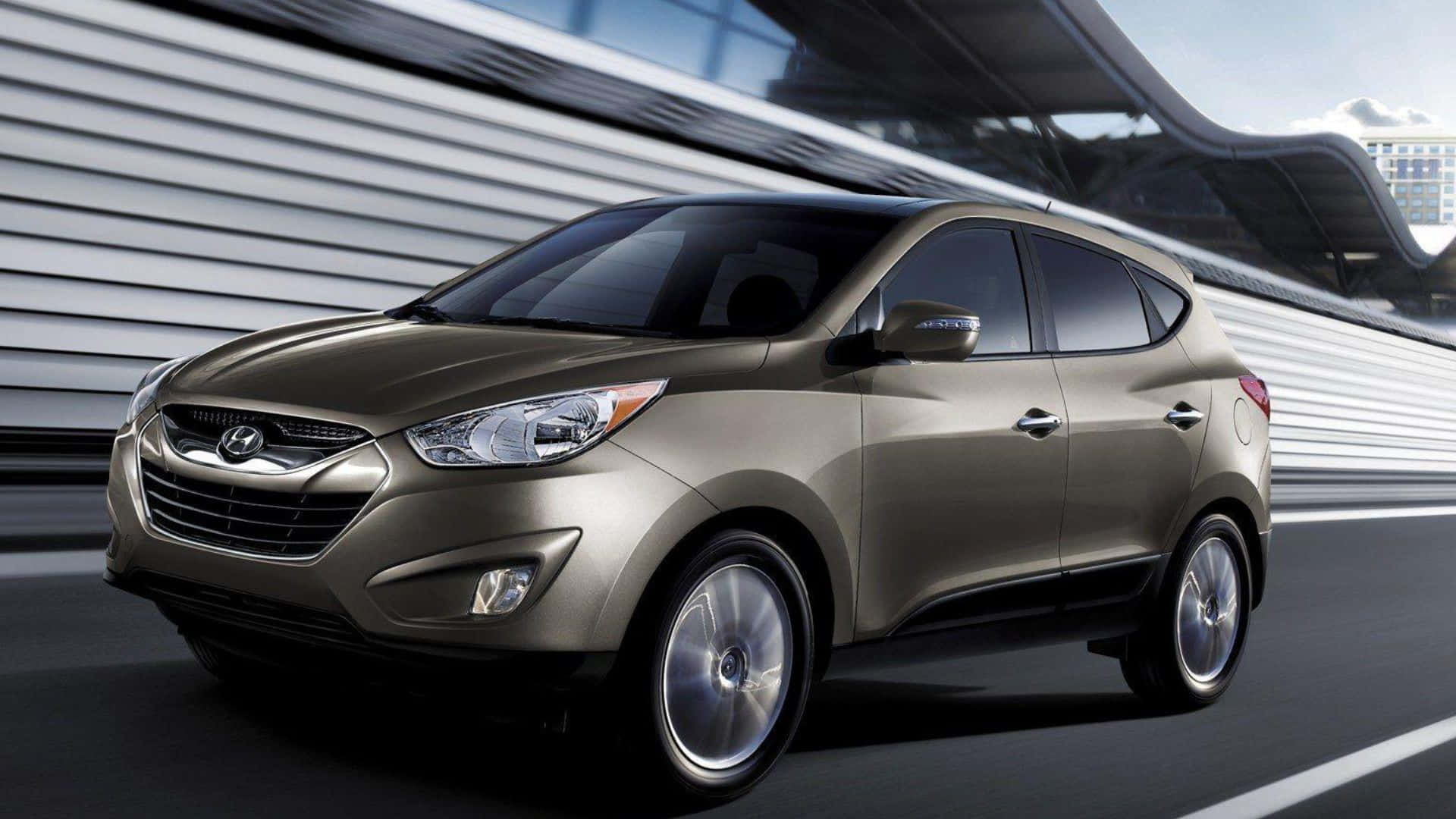 Hyundai Tucson 桌布 壁紙 — 一輛時尚的青銅色Hyundai Tucson SUV在現代高速公路上疾駛，背景帶有動態模糊和未來主義建築。