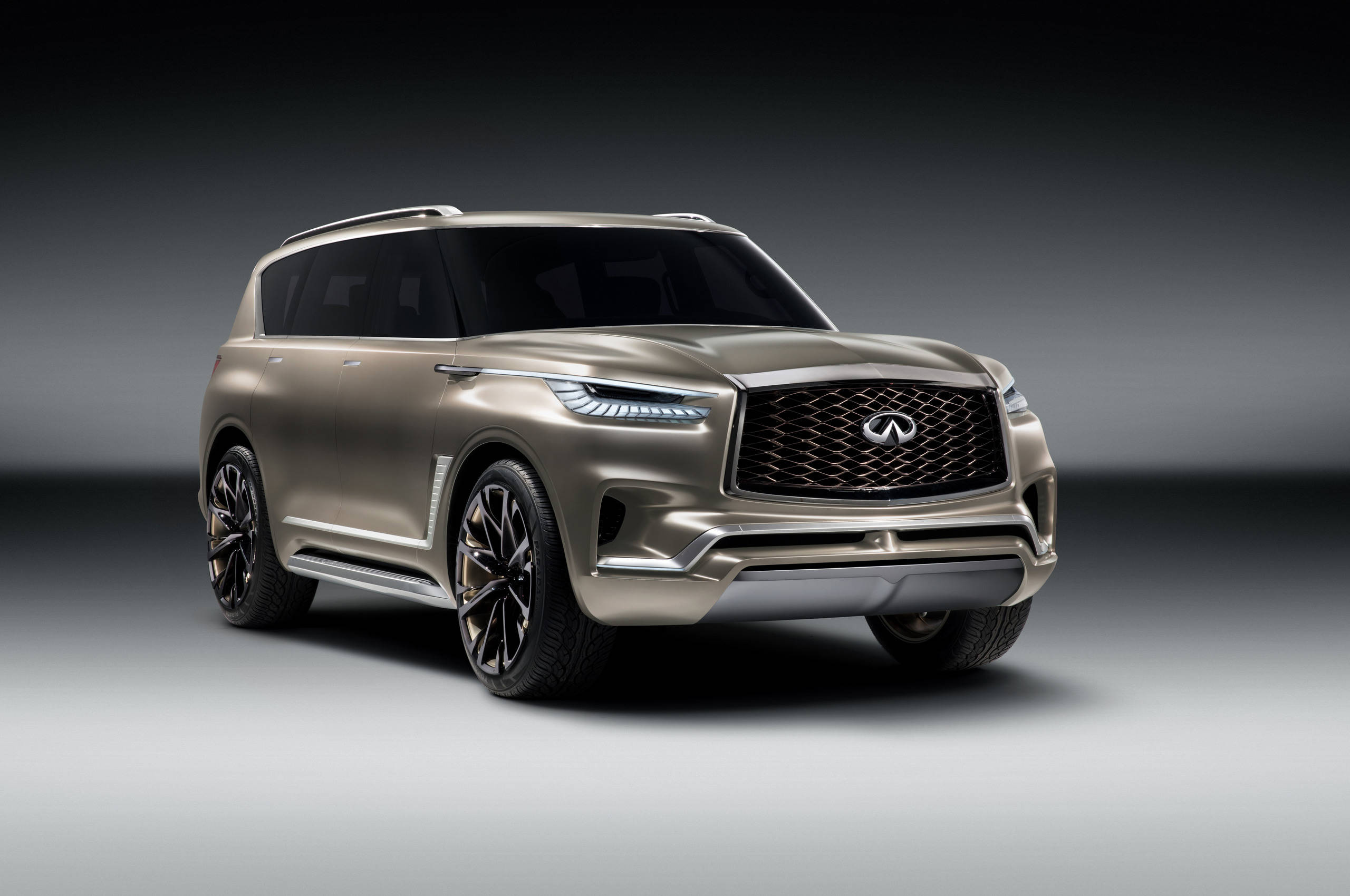 Infiniti 桌布 壁紙 — 一輛時尚的黃金Infiniti SUV，配備發光頭燈和黑色輪圈，在漸變灰色工作室背景前展現姿態。
