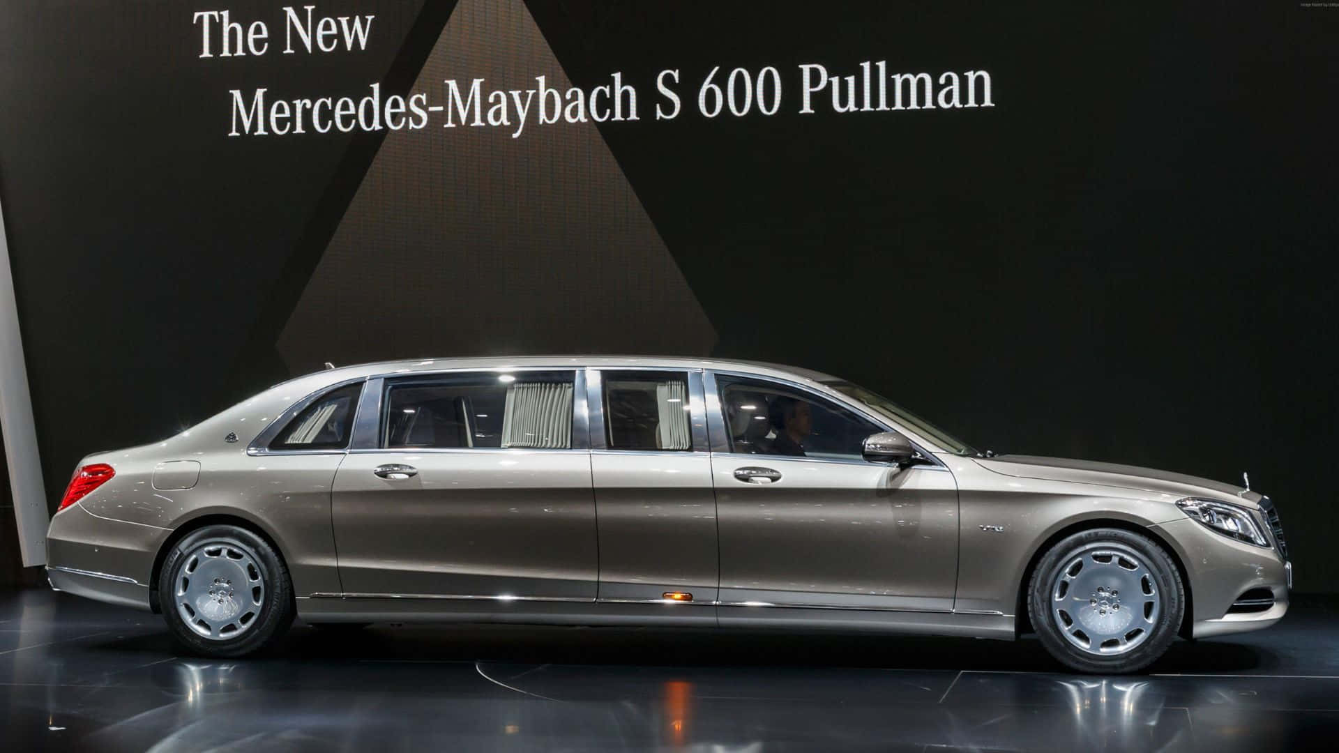 Maybach 桌布 壁紙 — 一輛時尚的黃金梅賽德斯-邁巴赫 S 600 Pullman 豪華轎車在黑暗舞台上的聚光燈下閃閃發光，背後有品牌標誌。