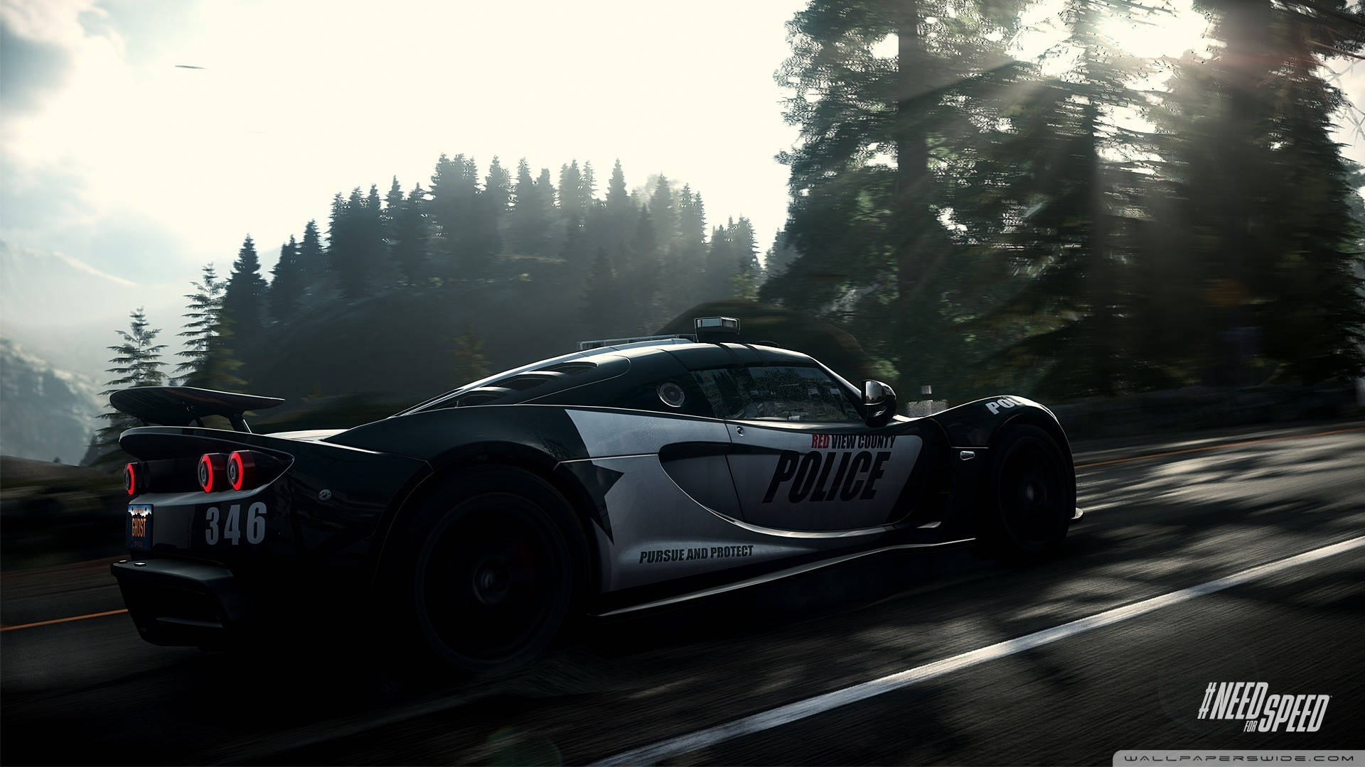 Need For Speed 桌布 壁紙 — 一輛時尚的黑白警用跑車在樹木茂密的山路上飛馳，陽光穿過樹林灑落。
