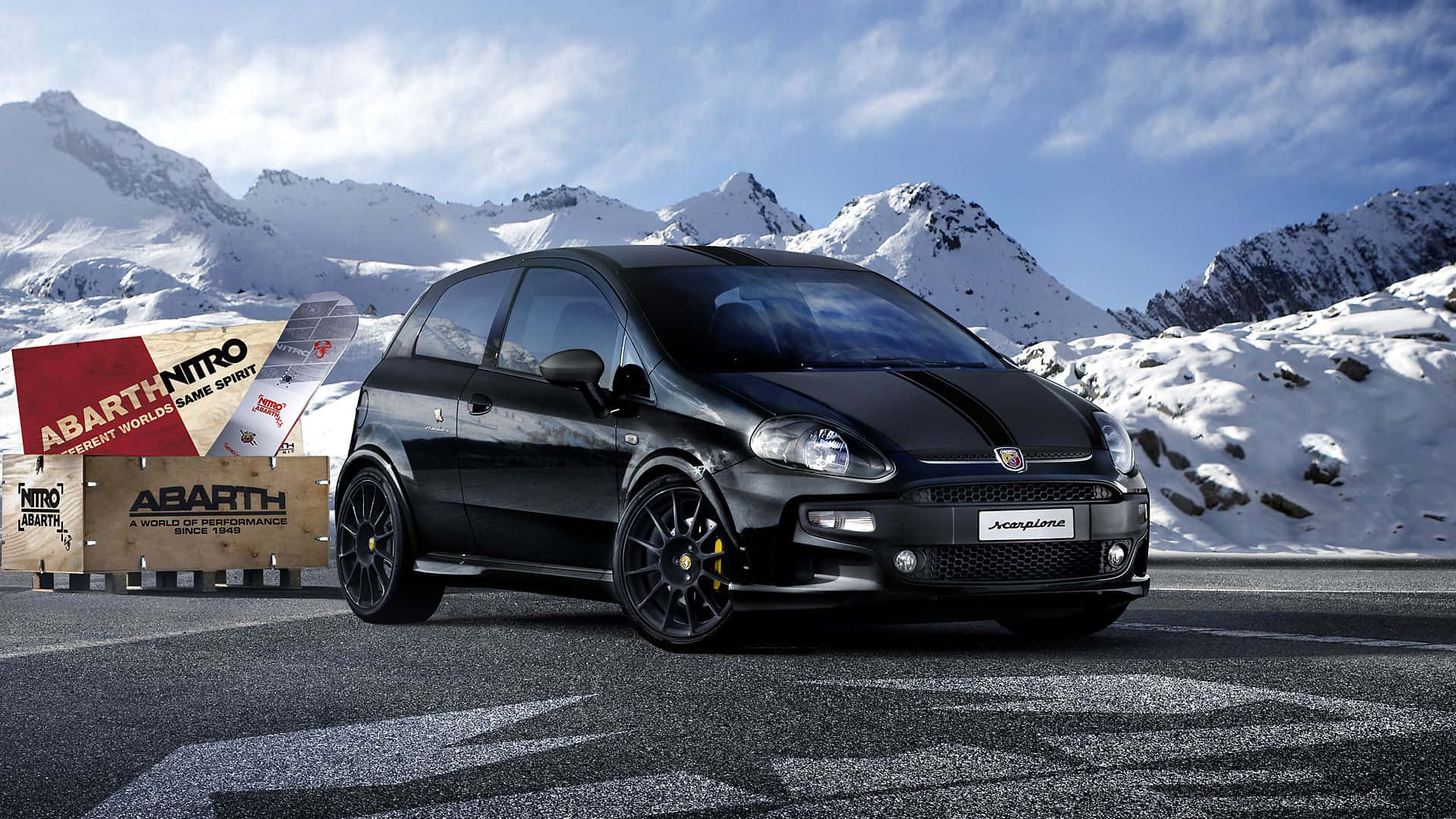 Fiat 500l 桌布 壁紙 — 一輛時尚的黑色 Abarth 500 Abarth Nitro 跑車停放在積雪的山路上，附近有滑雪裝備。