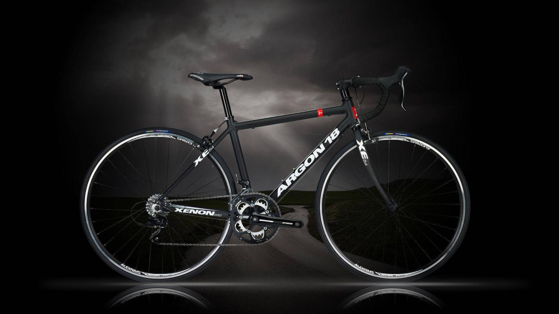 Bicycle 桌布 壁紙 — 一輛時尚的黑色 Argon 18 Xenon 公路自行車在黑暗暴風雨的天空和反射地面襯托下，顯得格外引人注目。