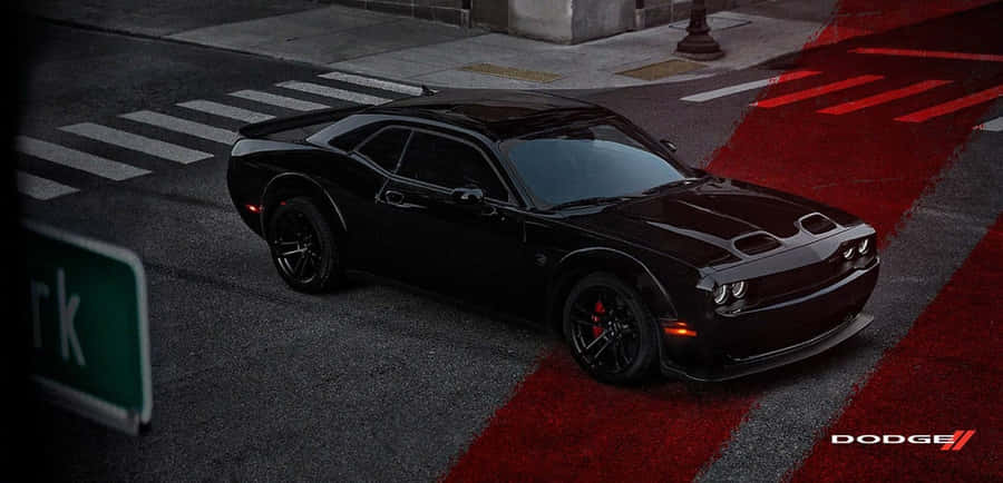 桌布 壁紙 — 一輛時尚的黑色 Dodge Challenger 停在十字路口，在昏暗的城市燈光下，路面有醒目的紅色標記。