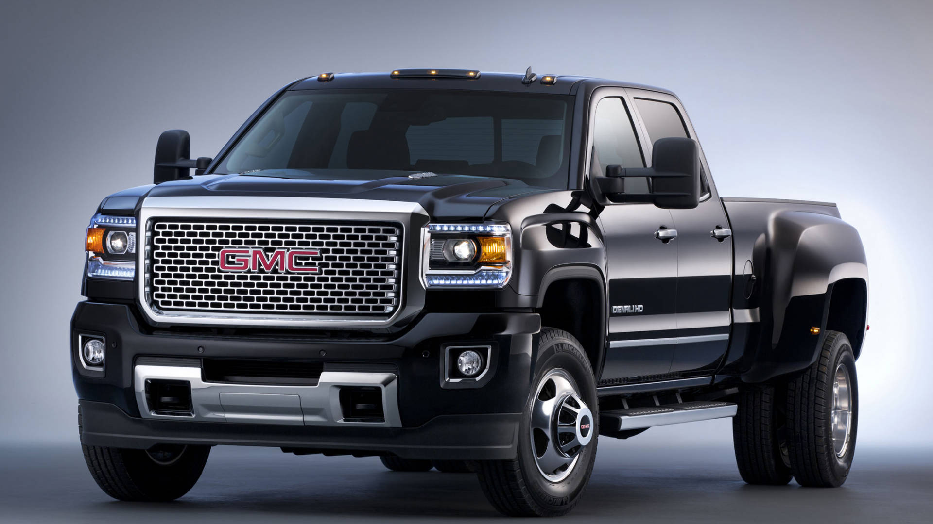 Gmc 桌布 壁紙 — 一輛時尚的黑色 GMC Sierra Denali 皮卡車，帶有鍍鉻飾邊和 LED 頭燈，在漸變灰色工作室背景前擺姿勢。