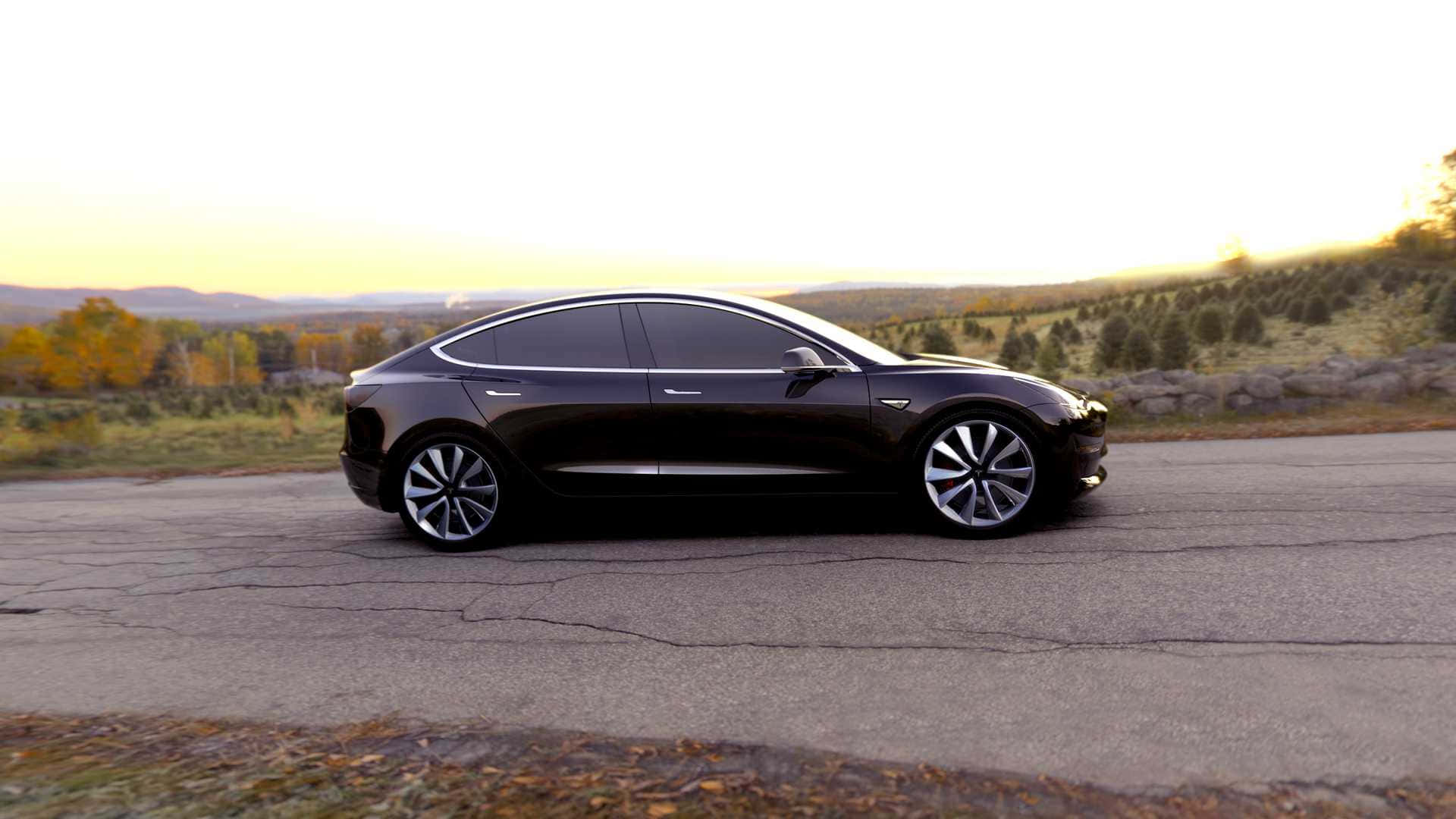Tesla Model 3 桌布 壁紙 — 一輛時尚的黑色 Tesla Model 3 停在裂開的柏油路上，正值黃金時刻，背景有秋樹和起伏的山丘。