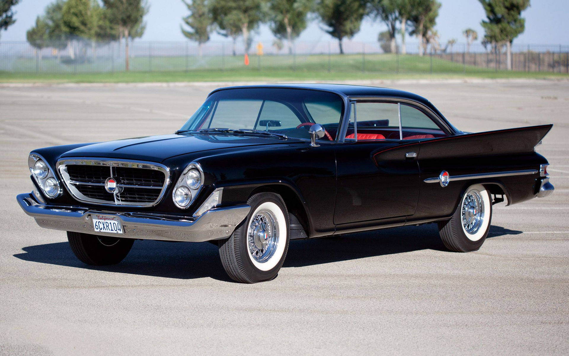 Chrysler 桌布 壁紙 — 一輛時尚的黑色1950年代經典汽車，配備白色側壁輪胎和鍍鉻細節，在明亮的日光下停放在瀝青停車場上。