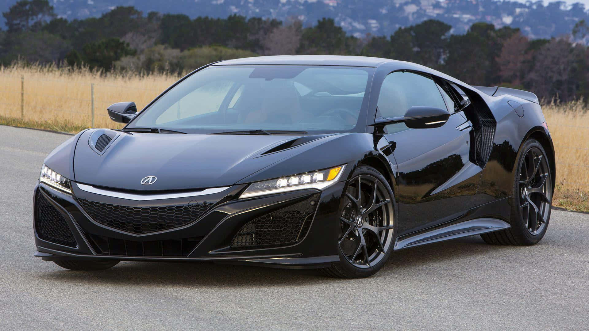 Acura Nsx 桌布 壁紙 — 一輛時尚的黑色Acura NSX跑車在鋪砌的道路上閃閃發光，背景是乾草和森林覆蓋的山丘。