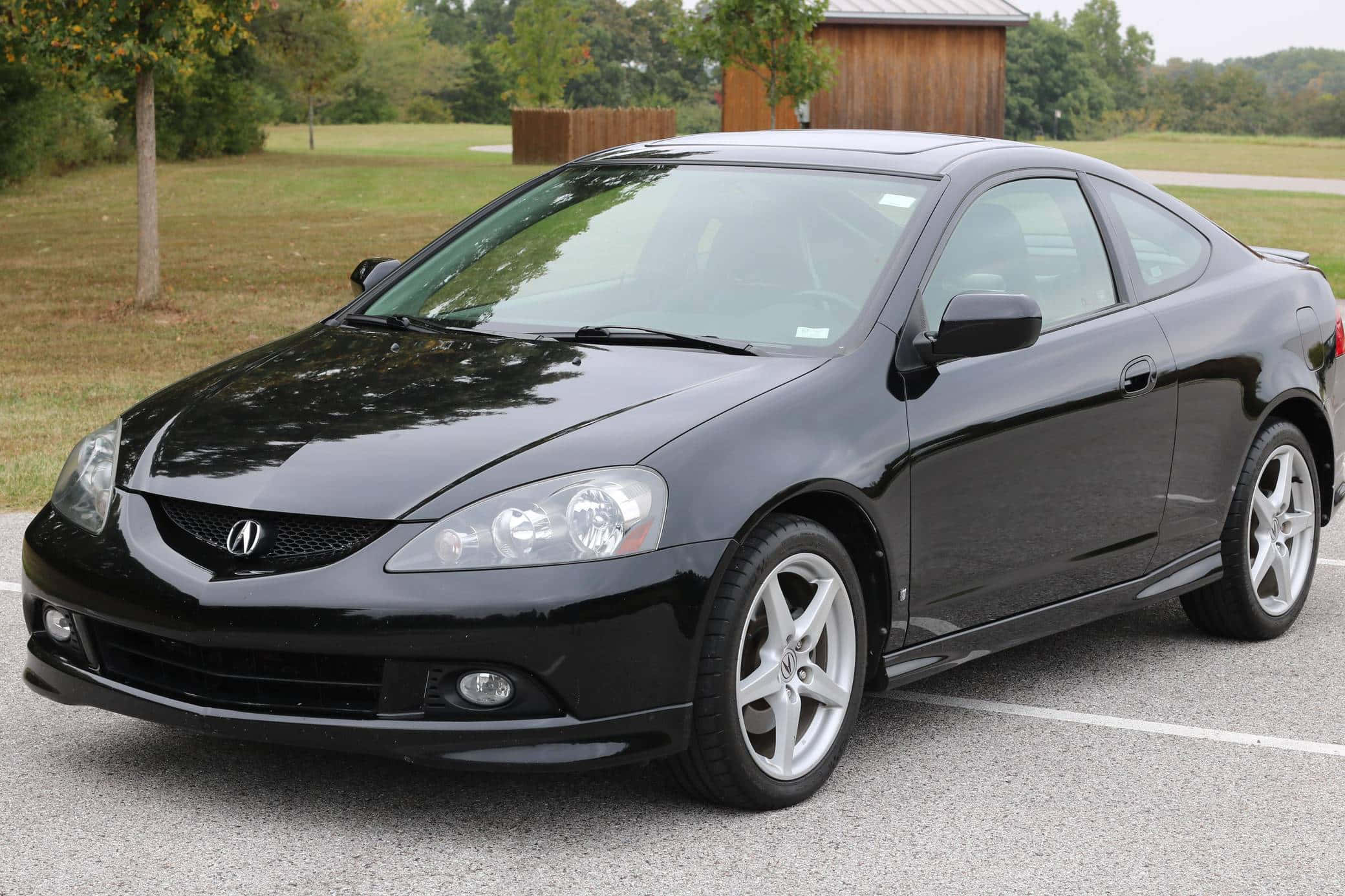 Acura Rsx 桌布 壁紙 — 一輛時尚的黑色Acura TSX雙門轎跑車停在柏油路上，背景有樹木和一個木棚。