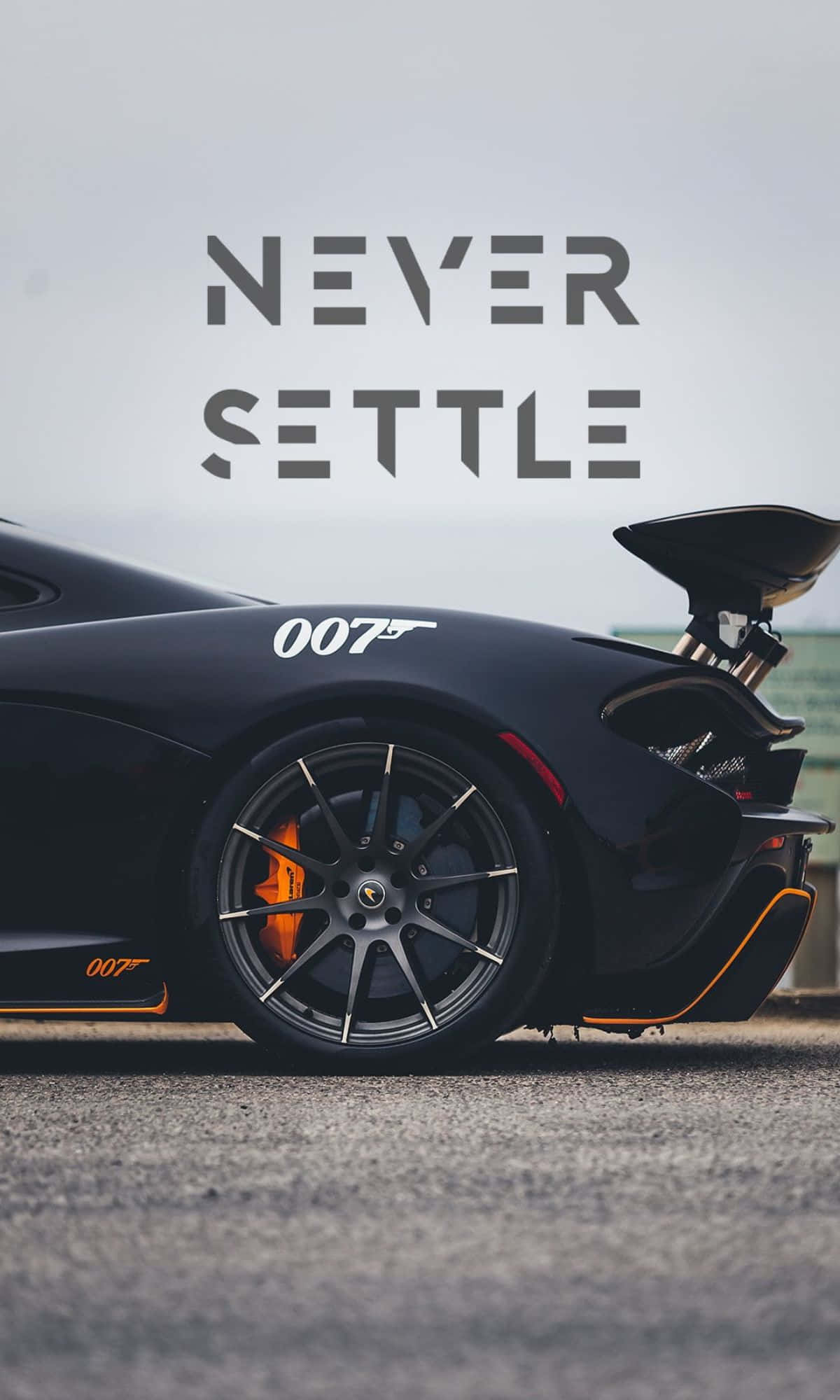 1200x2000 桌布 壁紙 — 一輛時尚的黑色Aston Martin，帶有橙色制動卡鉗和「007」貼紙，停泊在陰天下的瀝青路面上。
