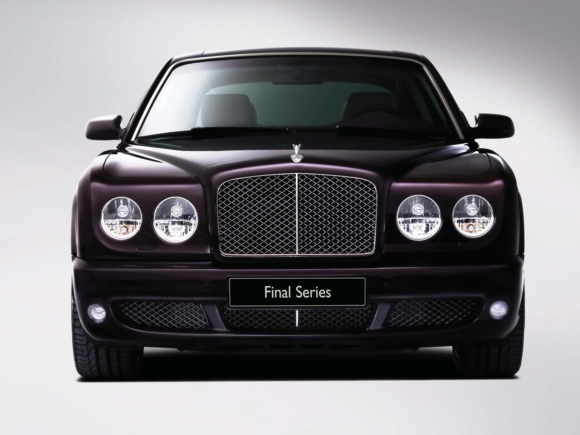 桌布 壁紙 — 一輛時尚的黑色Bentley Final Series轎車正面朝前，帶有鍍鉻格柵和圓形頭燈，背景為中性工作室背景。