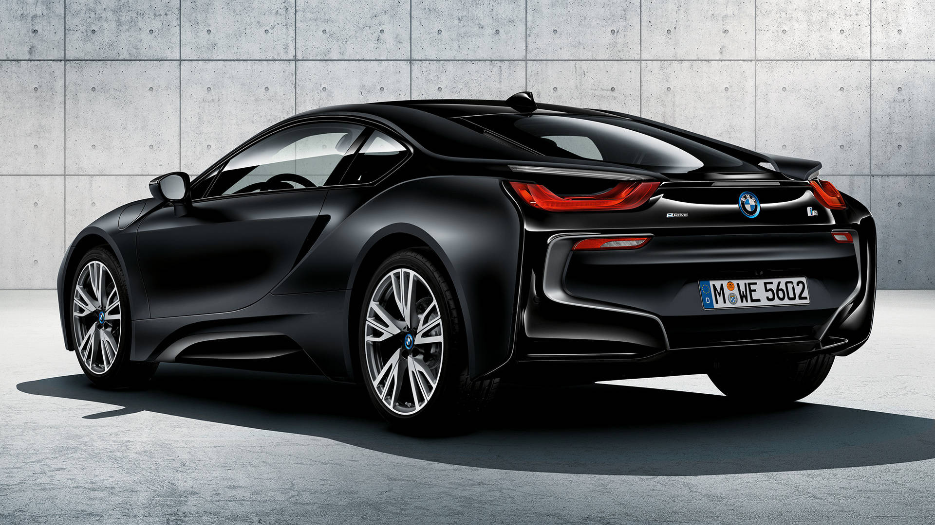 Black Bmw 桌布 壁紙 — 一輛時尚的黑色BMW i8跑車，帶紅色尾燈，停放在有紋理的混凝土牆旁。