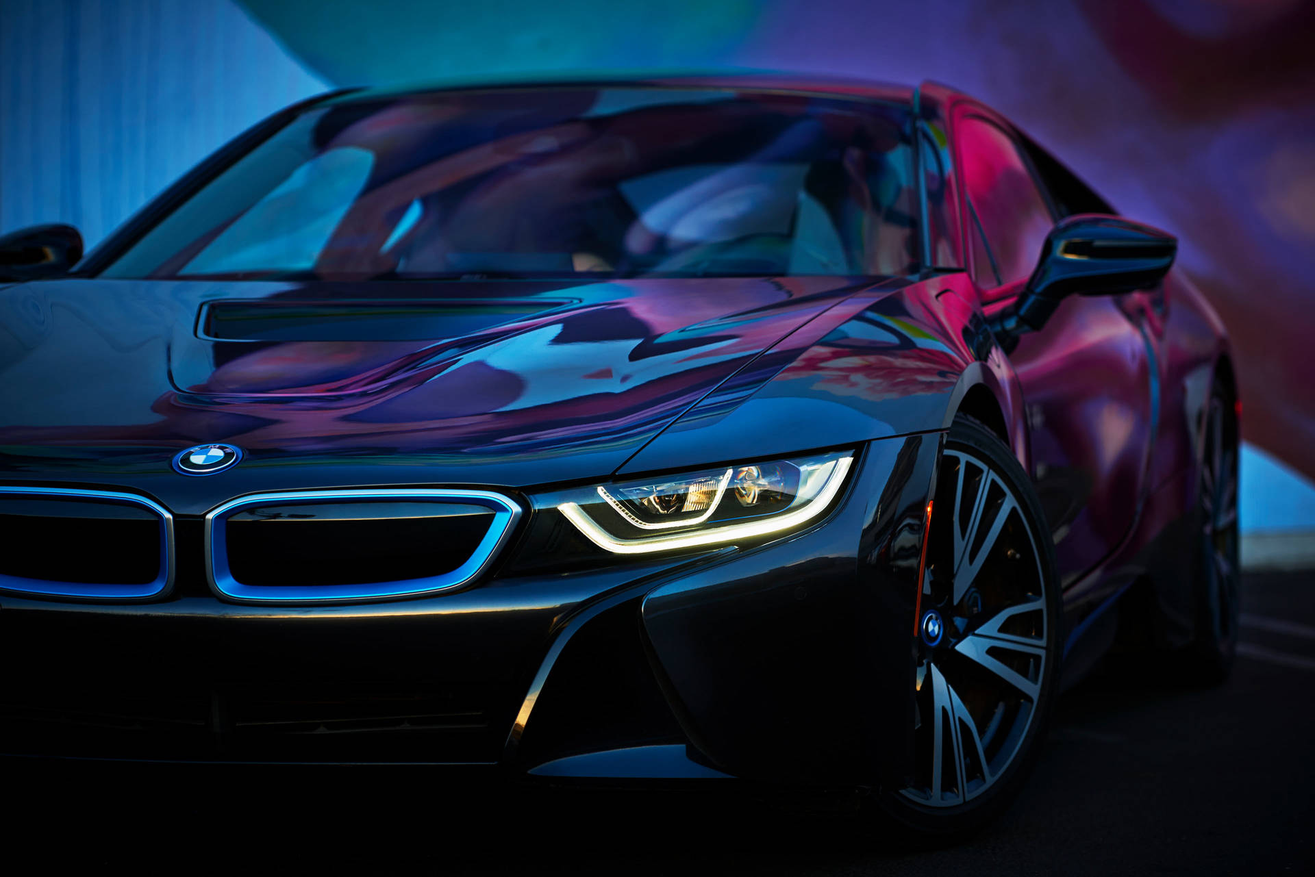 BMW 動圖 桌布 壁紙 — 一輛時尚的黑色BMW i8跑車在黑暗的攝影棚中，在鮮豔的藍色和紫色霓虹燈下閃閃發光。