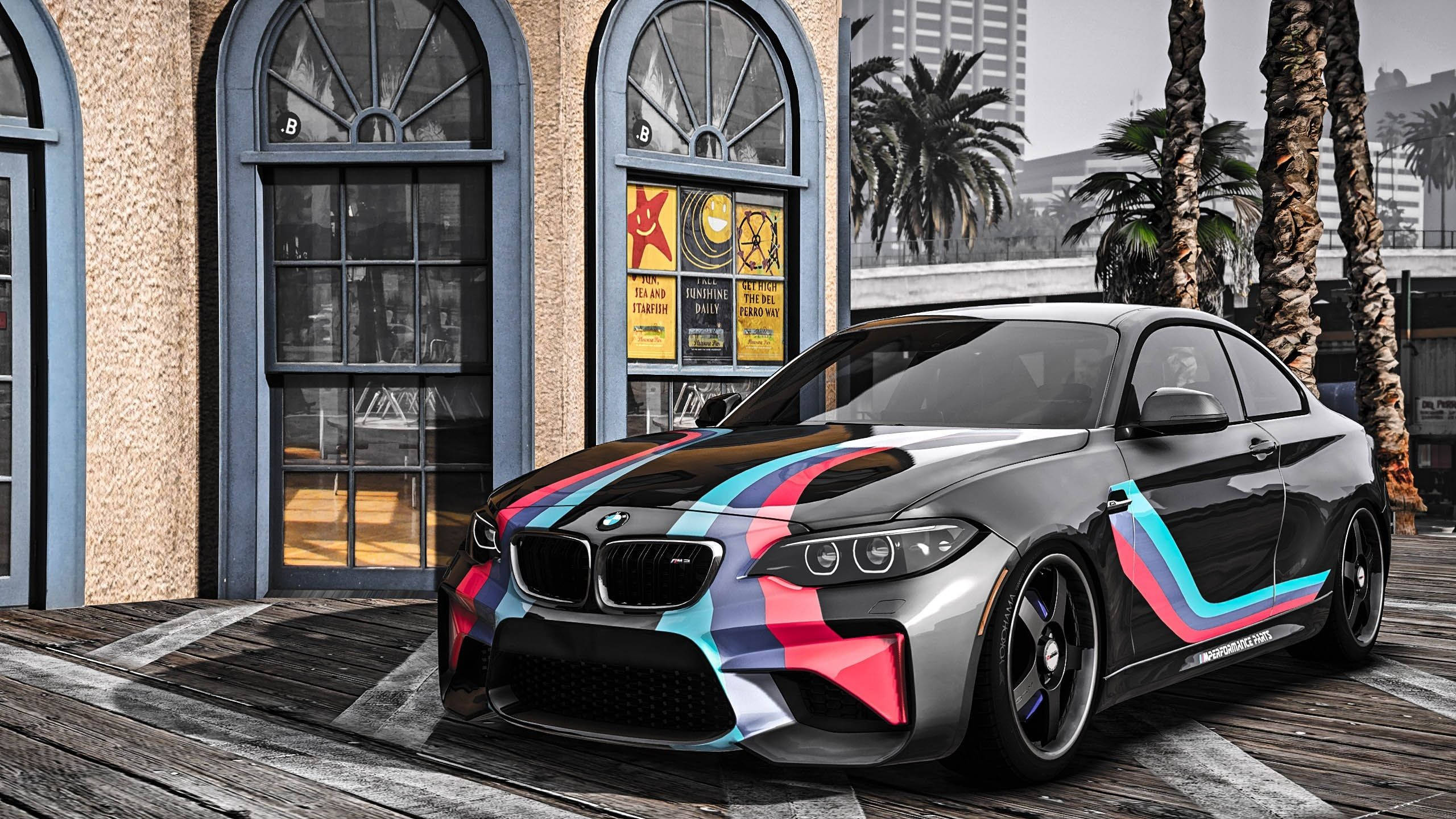 電玩遊戲 桌布 壁紙 — 一輛時尚的黑色BMW M2雙門轎跑車，帶有鮮豔的粉紅、藍和白賽車條紋，停泊在風化的木碼頭上，旁邊有棕櫚樹和一座復古建築。