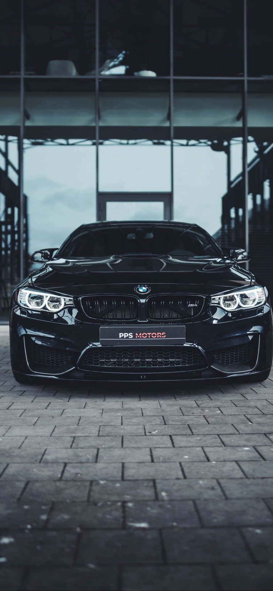 黑色BMW M4跑車停放在現代玻璃牆車庫的磚地上。 — Project Cars 壁紙