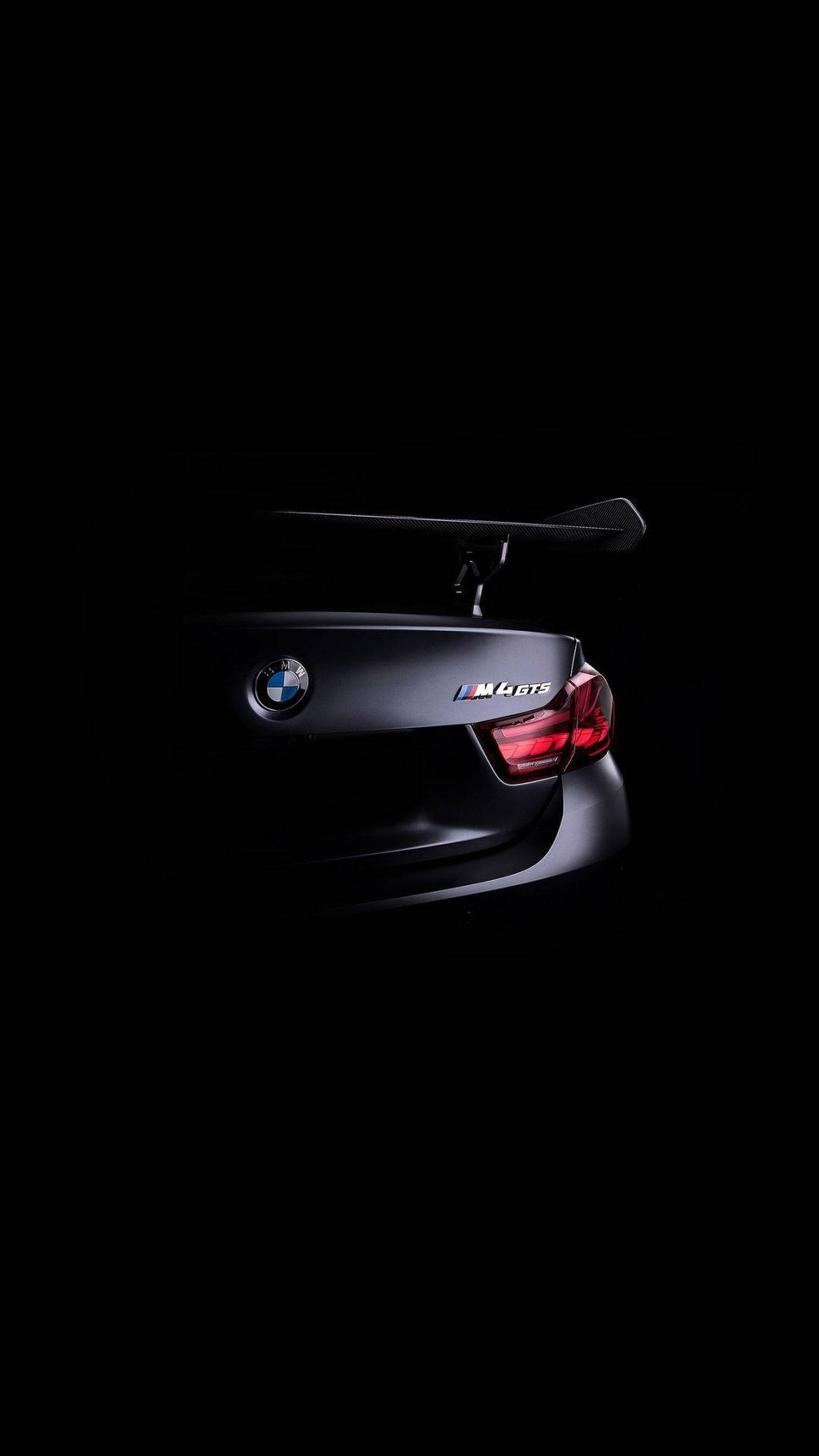 BMW 動圖 桌布 壁紙 — 一輛時尚的黑色BMW M6 GTS跑車，在純黑色背景下被戲劇性的燈光照亮。