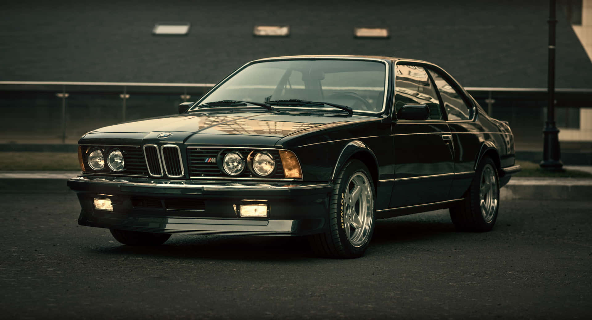 BMW E30 壁紙 — 一輛時尚的黑色BMW M6轎跑車停在瀝青路上，背景有黑暗的建築物和街燈。