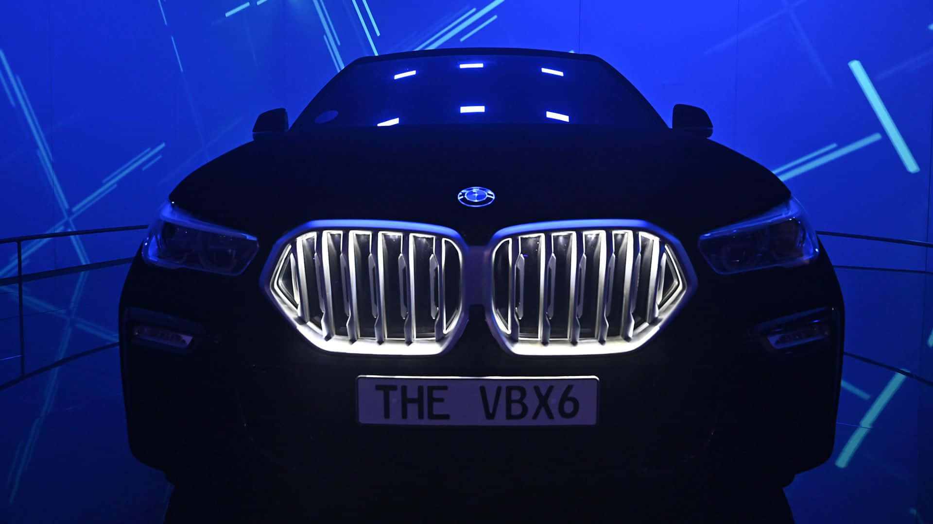 Vantablack 桌布 壁紙 — 一輛時尚的黑色BMW SUV，帶有發光的鍍鉻格柵和「THE VBX6」車牌，在充滿活力的藍色霓虹燈下展示。