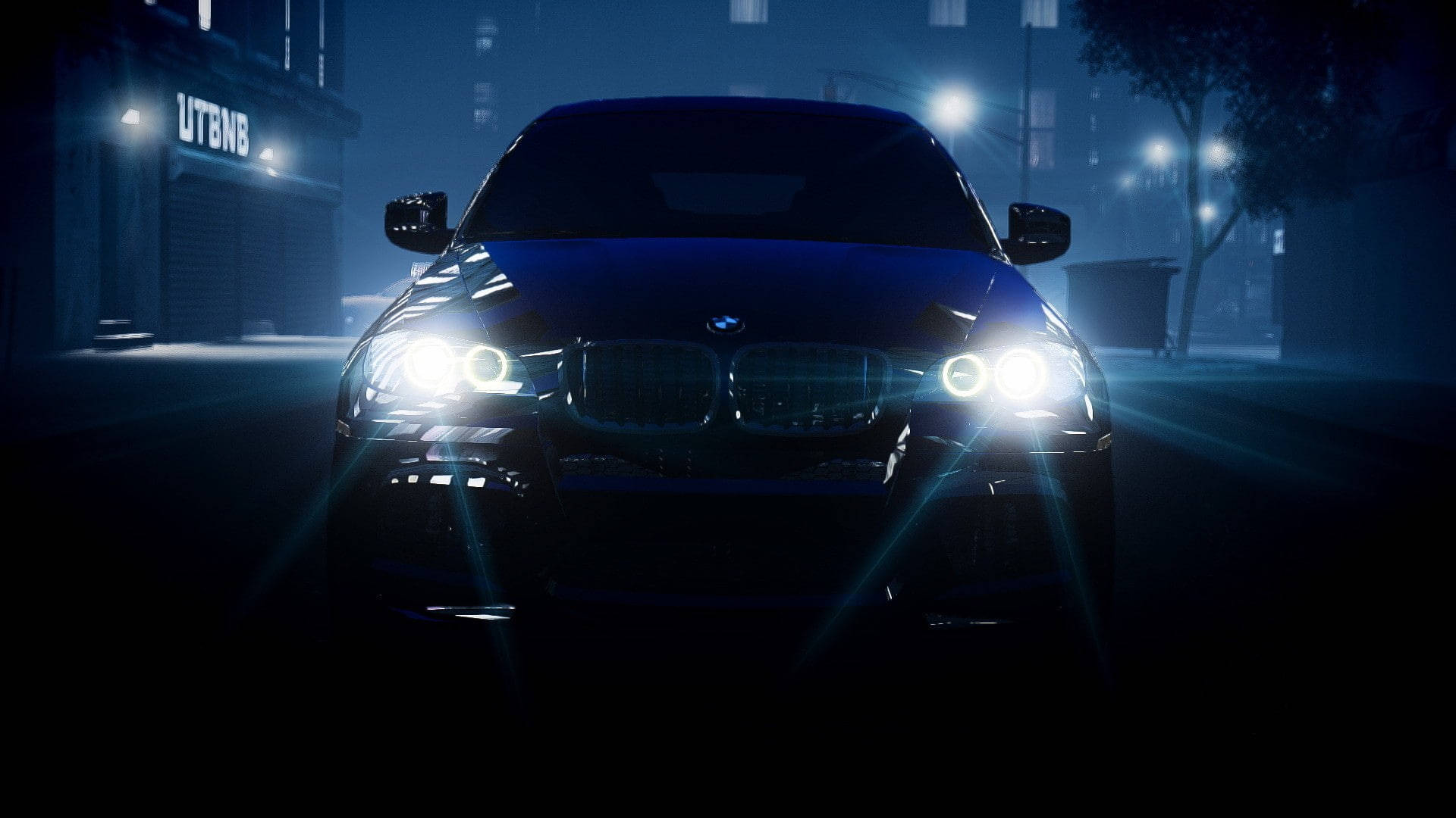 m 桌布 壁紙 — 一輛時尚的黑色BMW SUV在夜間主導著霧氣瀰漫的城市街道，明亮的車頭燈劃破迷霧，背景中路燈閃爍。