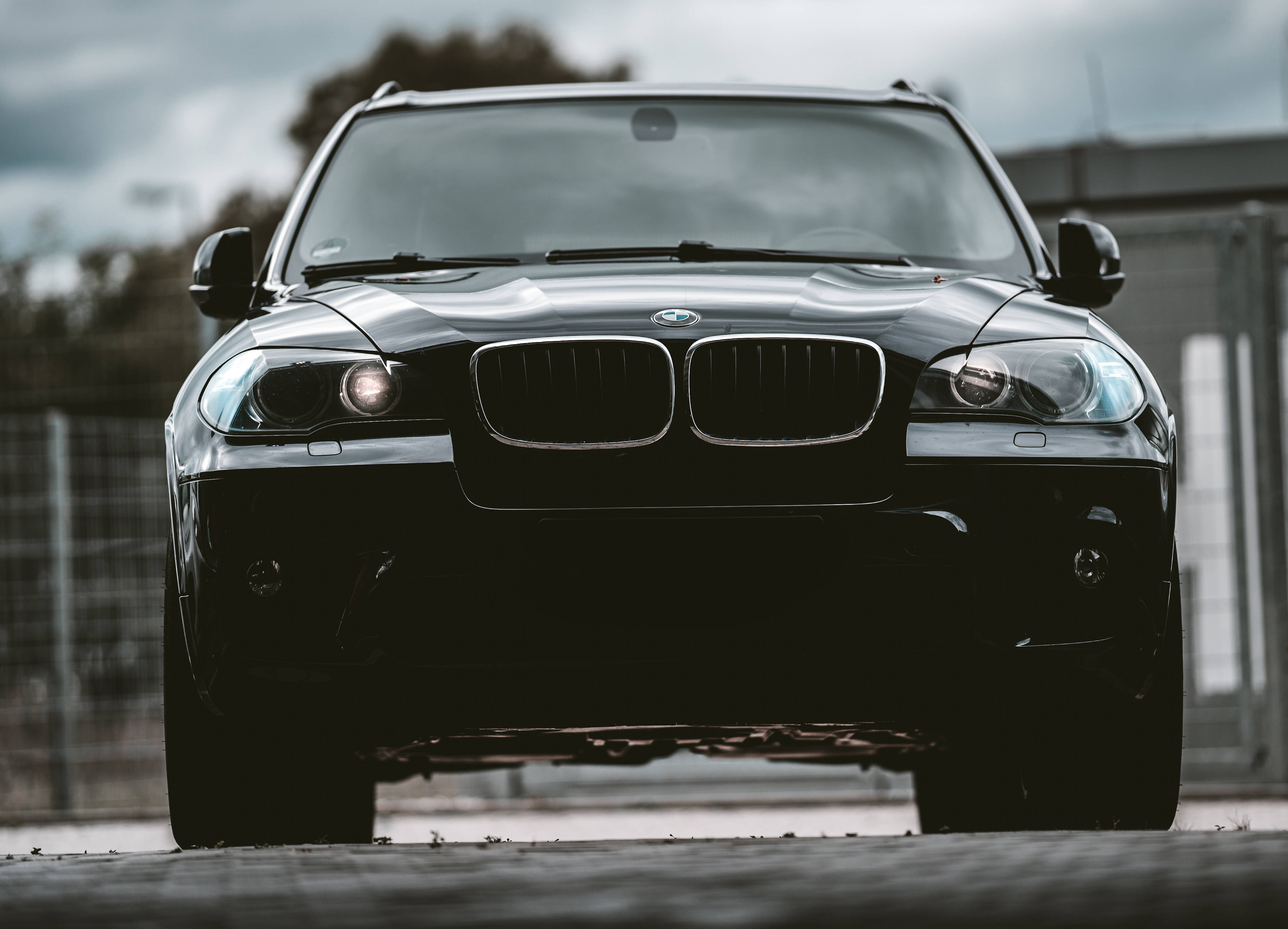Black Bmw 桌布 壁紙 — 一輛時尚的黑色BMW SUV在陰天向前方亮著車頭燈。
