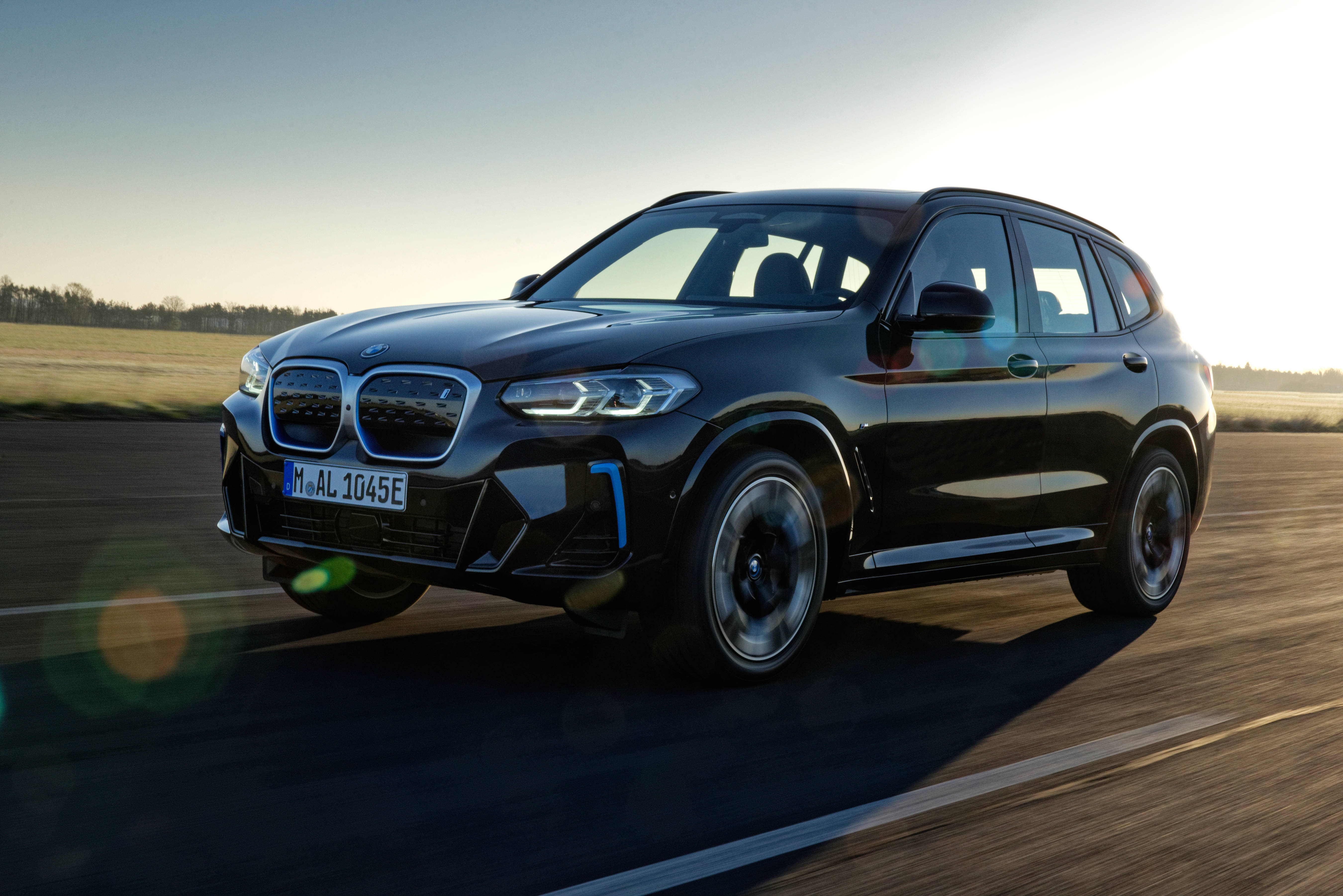 Black Bmw 桌布 壁紙 — 一輛時尚的黑色BMW X3 SUV在陽光明媚的道路上疾馳，動態模糊和鏡頭光暈增強了其動感存在感。