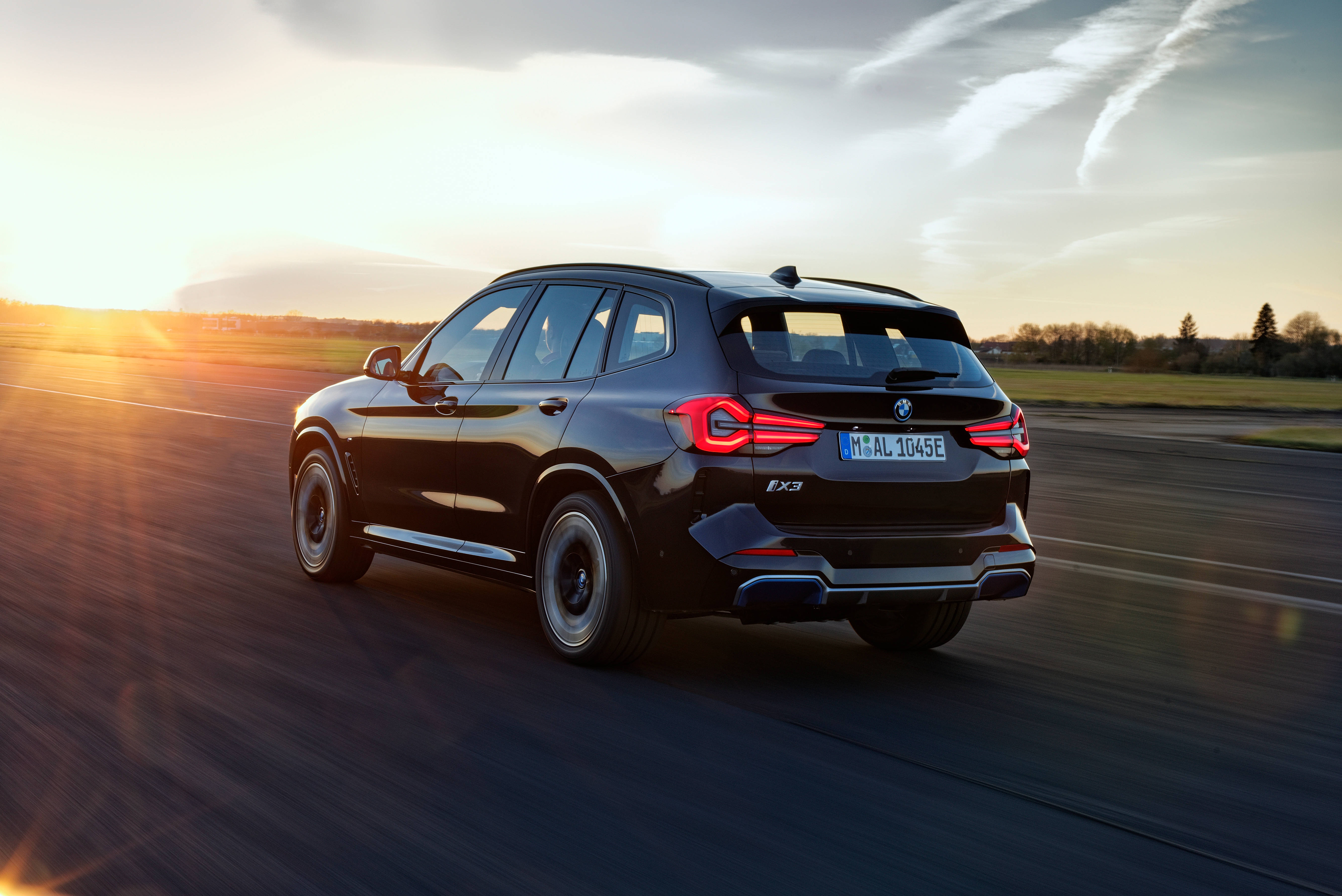 Black Bmw 桌布 壁紙 — 一輛時尚的黑色BMW X3 SUV在日落時分行駛在高速公路上，地平線上的金色光芒閃耀。