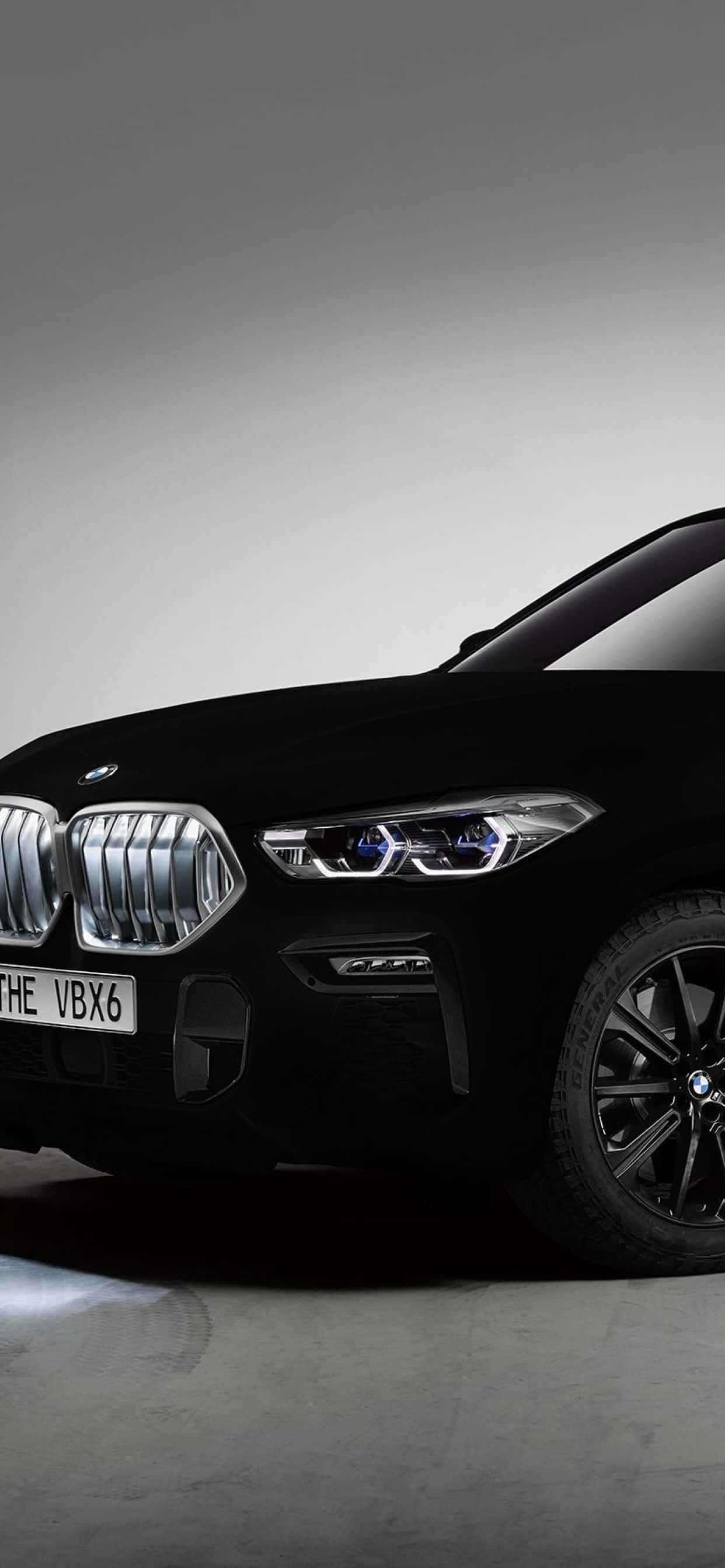 Vantablack 桌布 壁紙 — 一輛時尚的黑色BMW X6 SUV，配備發光頭燈和鍍鉻飾邊，在簡約灰色工作室背景下展示。