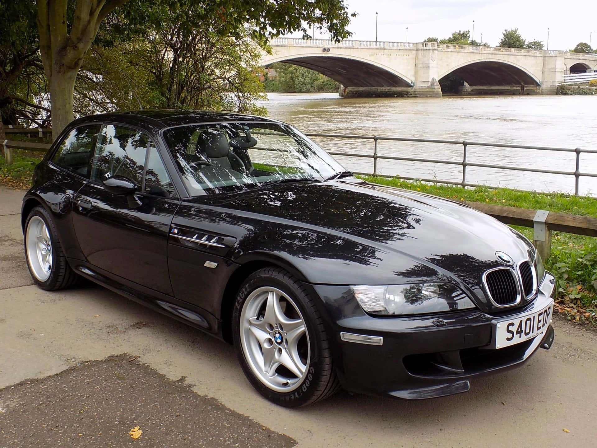 Bmw Z3 桌布 壁紙 — 一輛時尚的黑色BMW Z3敞篷跑車停在河邊，背景是一座石橋。