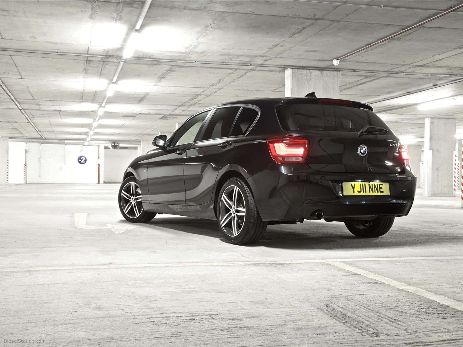 Bmw 1 Series 桌布 壁紙 — 一輛時尚的黑色BMW掀背車停在光線昏暗的混凝土地下停車場，尾燈發光。