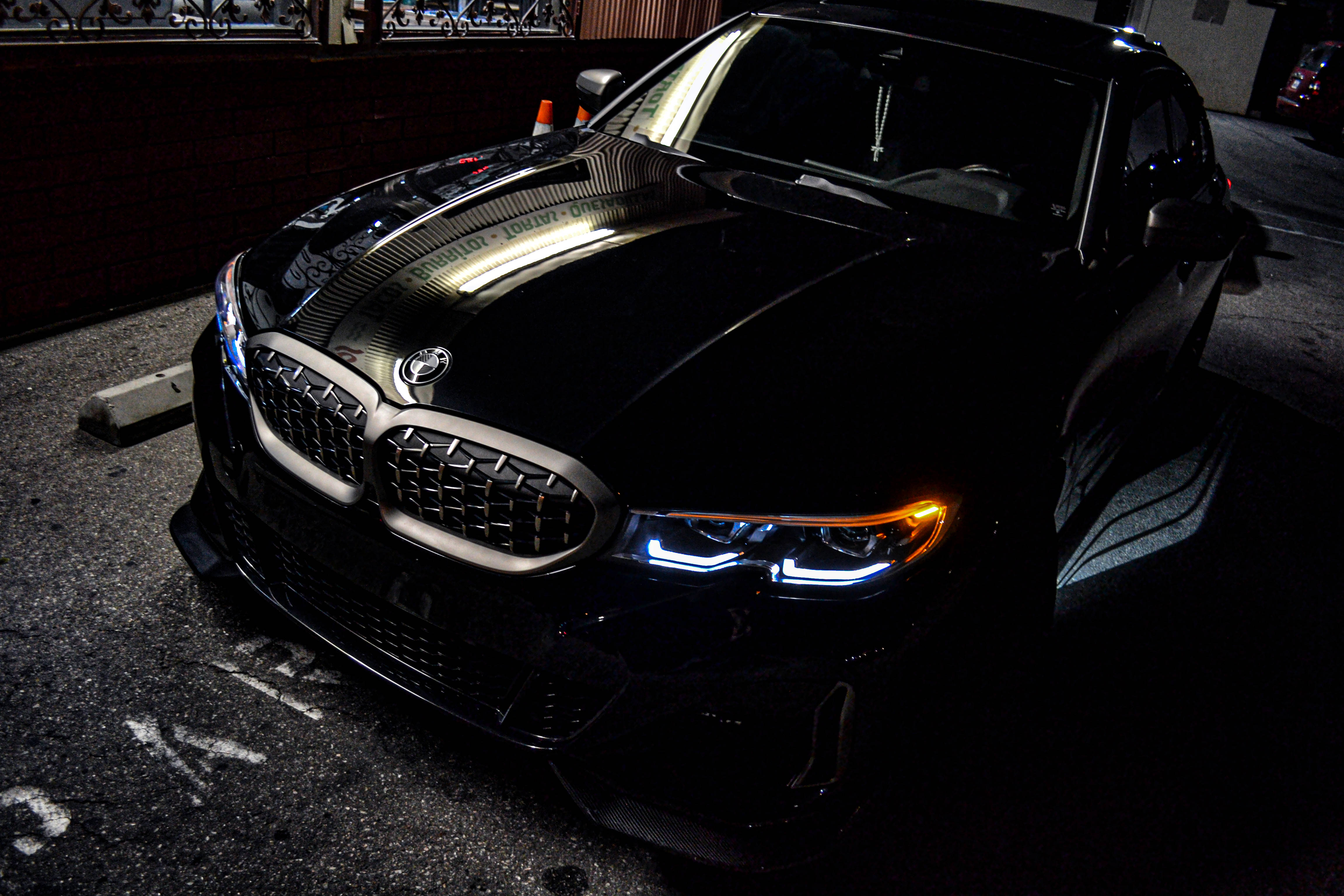 4K BMW 壁紙 桌布 壁紙 — 一輛時尚的黑色BMW跑車在夜間昏暗的城市停車場中，在人造燈光下閃閃發光。