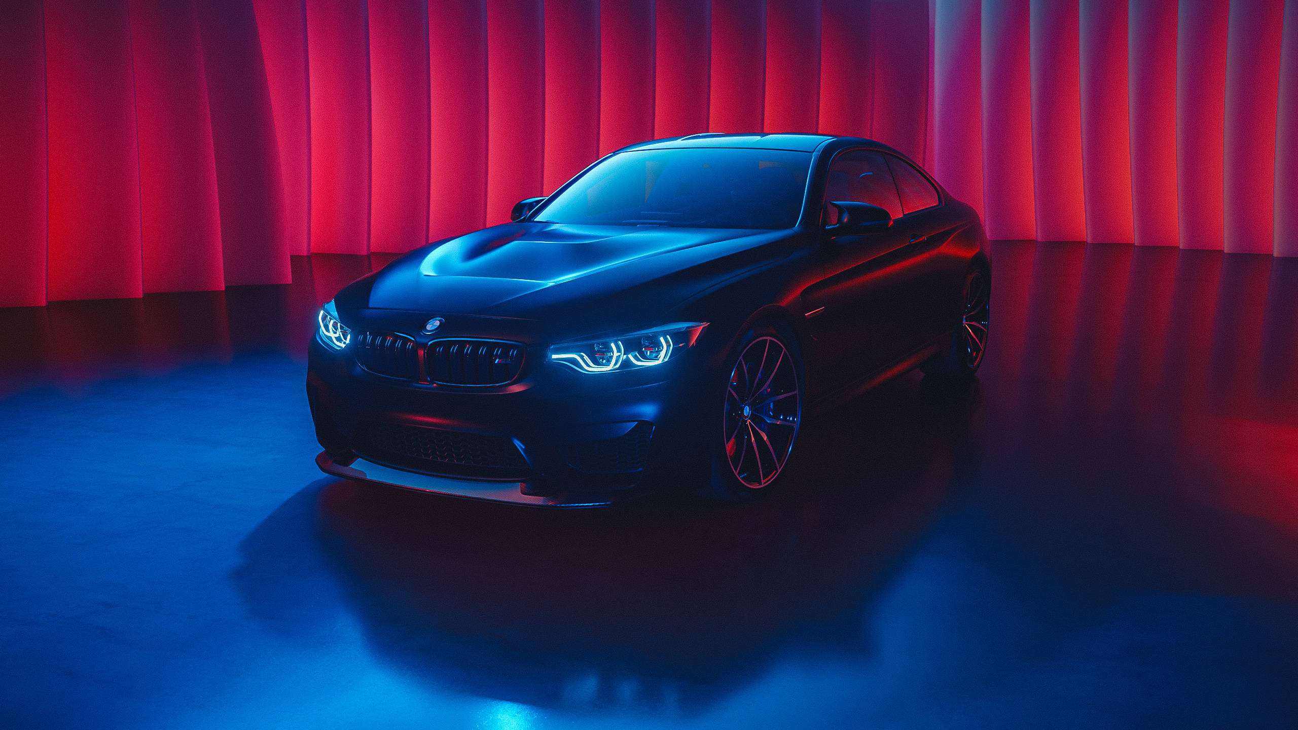 m 桌布 壁紙 — 一輛時尚的黑色BMW跑車在戲劇性的紅色和藍色工作室燈光下，以窗簾背景為襯托閃耀。