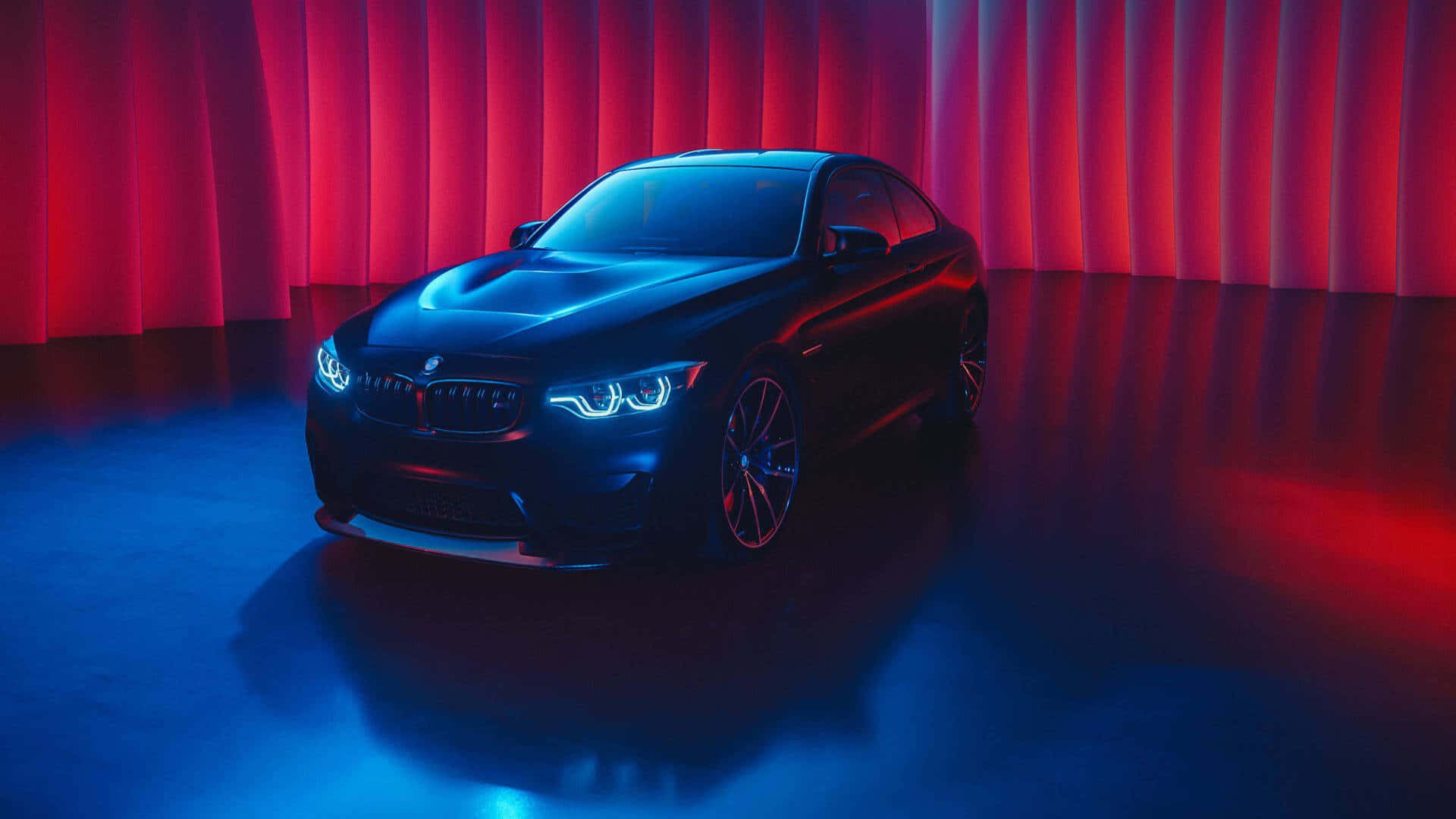 Bmw M Series 桌布 壁紙 — 一輛時尚的黑色BMW跑車在戲劇性的紅色和藍色工作室燈光下，以窗簾背景為襯托閃耀著光芒。