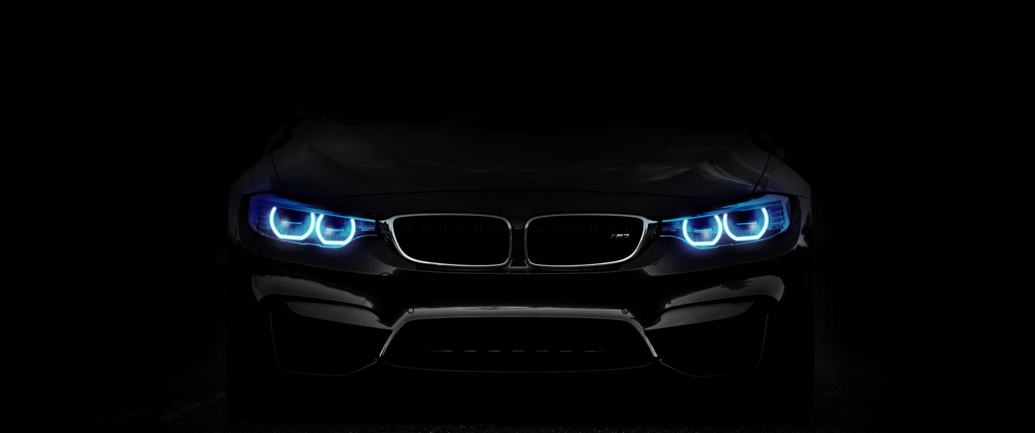 背景 桌布 壁紙 — 一輛時尚的黑色BMW跑車在漆黑背景下散發出鮮豔的藍色車頭燈光芒。