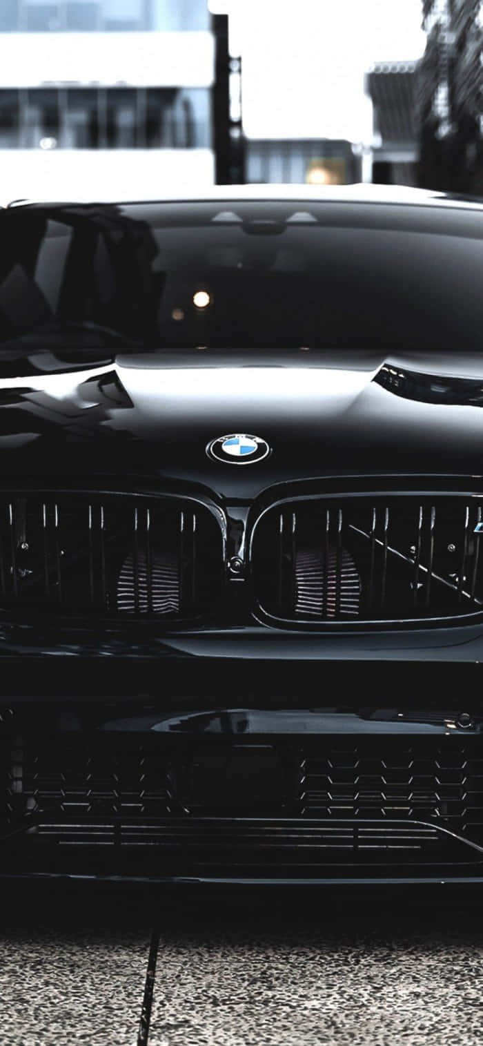 桌布 壁紙 — 一輛時尚的黑色BMW跑車在都市日光下閃耀，具有光澤表面和銳利的格柵細節。