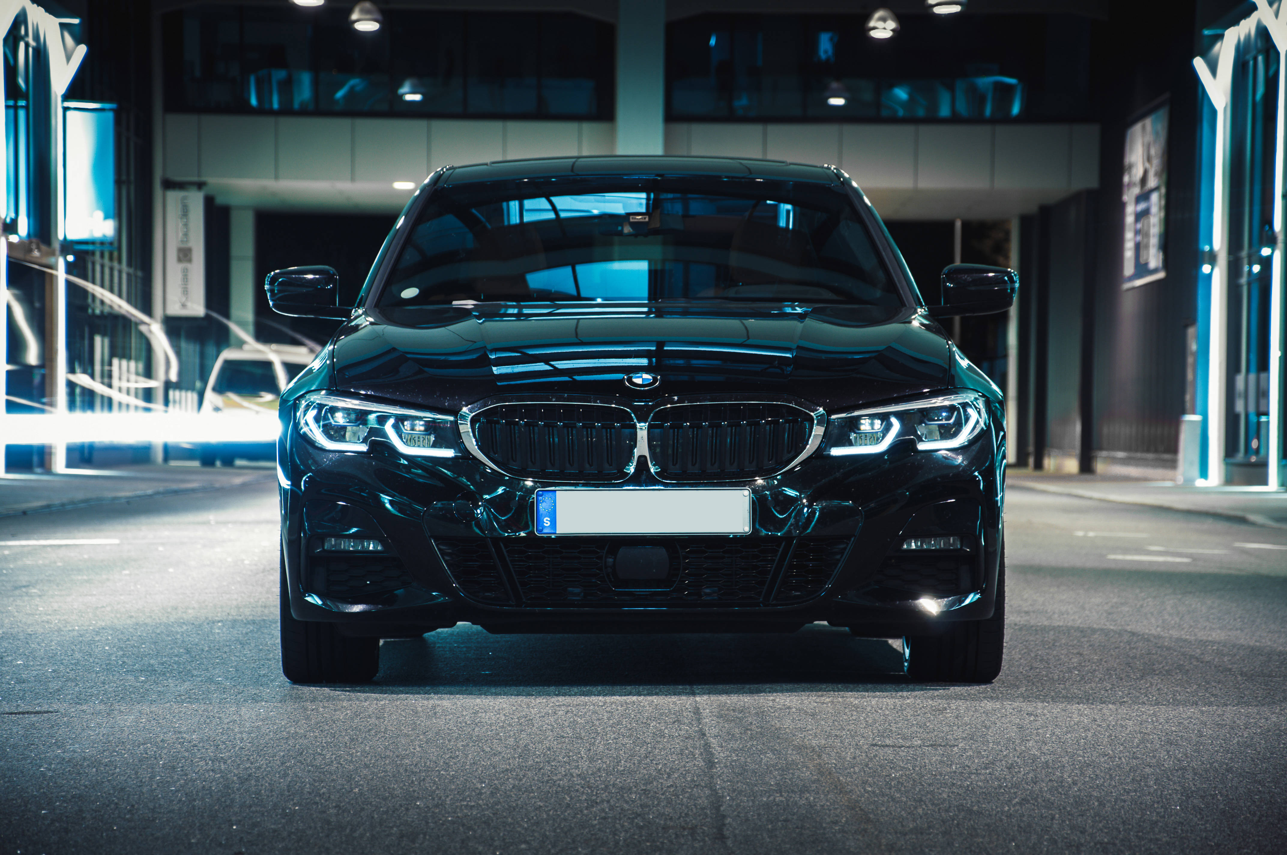 Black Bmw 桌布 壁紙 — 一輛時尚的黑色BMW轎車在現代都市夜晚的霓虹燈下閃耀。