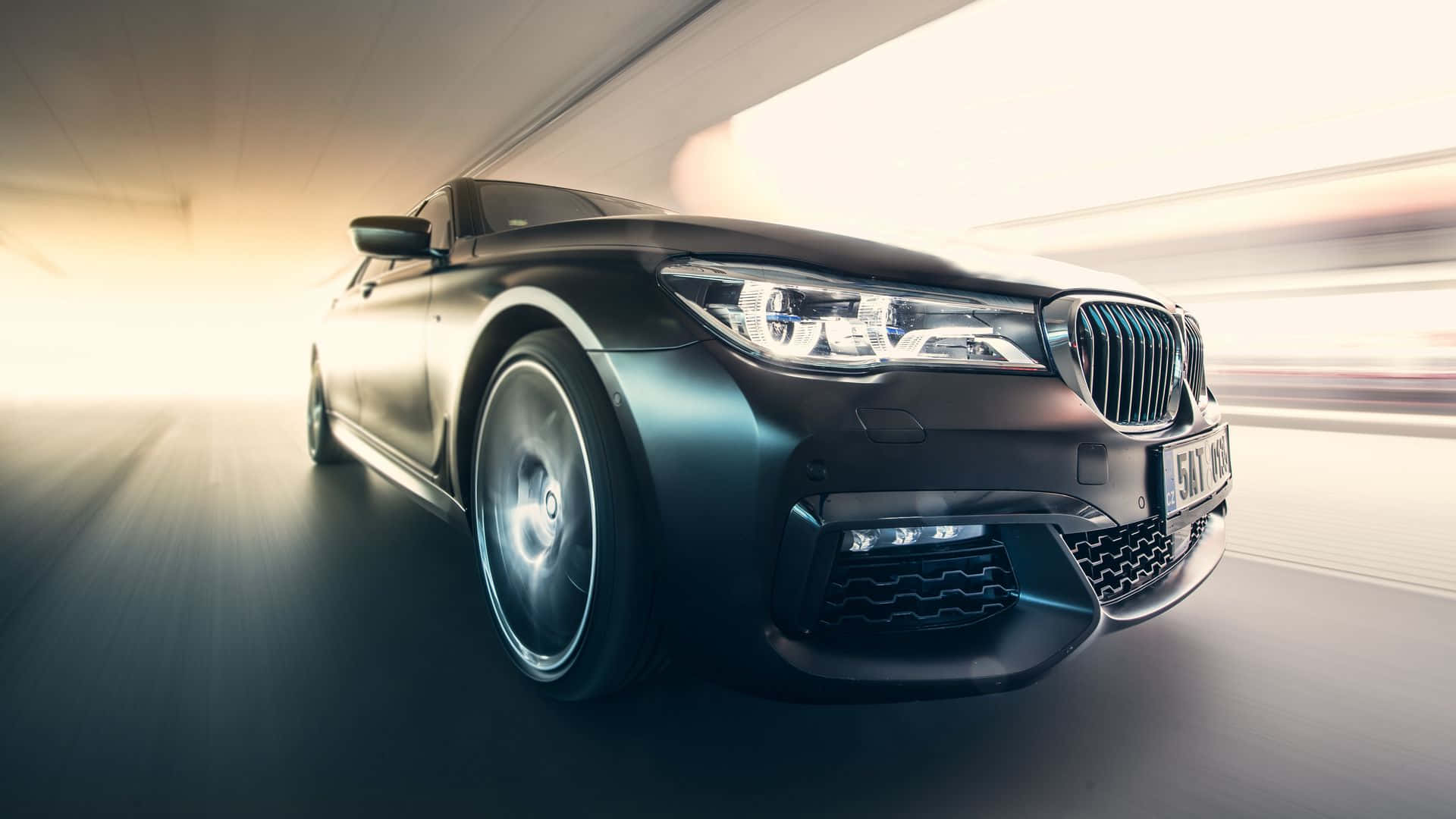 Car Images HD 桌布 壁紙 — 一輛時尚的黑色BMW轎車在隧道中疾馳，動態模糊掠過其閃亮的車頭燈。