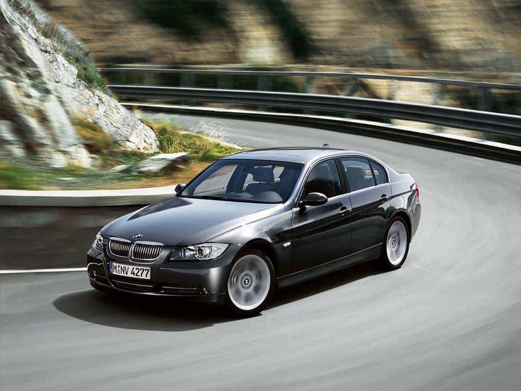 BMW 動圖 桌布 壁紙 — 一輛時尚的黑色BMW轎車沿著蜿蜒的山路疾馳，風景模糊。