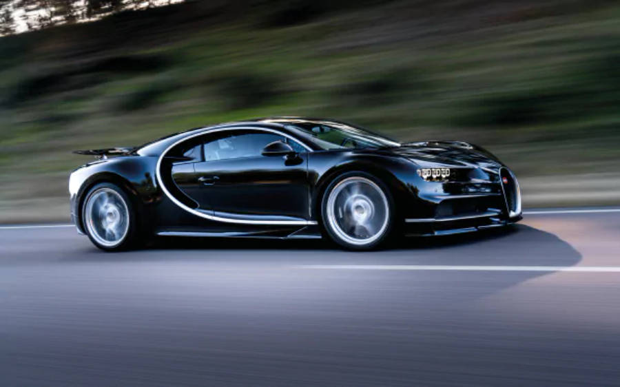 4K 桌布 壁紙 — 一輛時尚的黑色Bugatti Chiron在道路上疾馳，背景是模糊的綠意。
