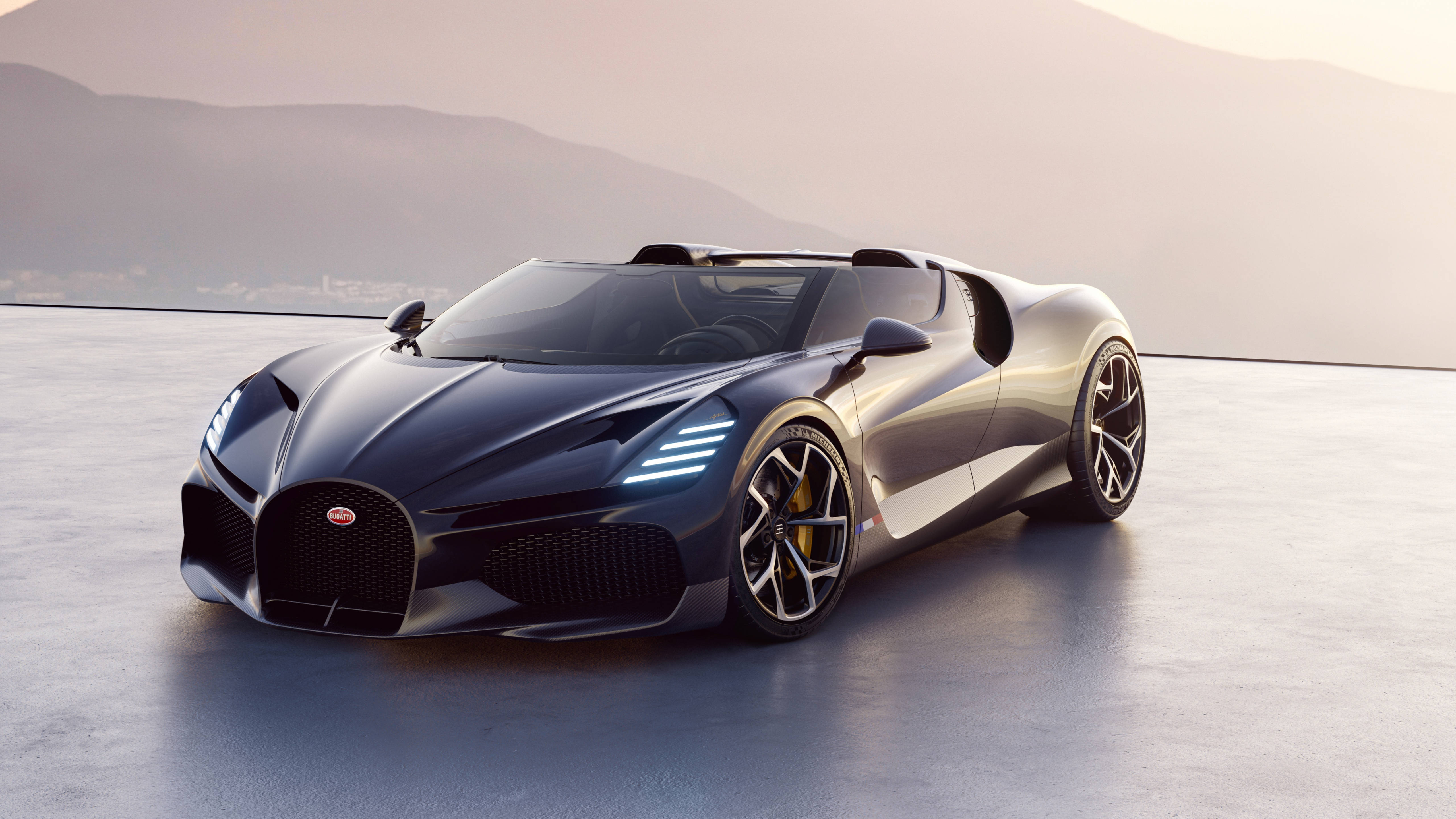 布加迪 桌布 壁紙 — 一輛時尚的黑色Bugatti Chiron Super Sport 300+敞篷車在廣闊的混凝土平台上，在柔和的金色燈光下閃閃發光，背景是朦朧的山脈。