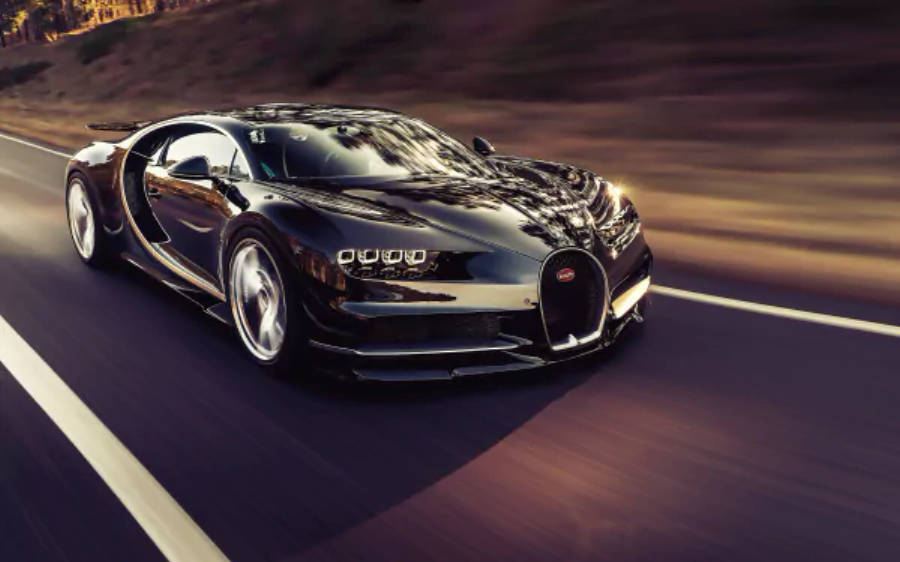 4K 桌布 壁紙 — 一輛時尚的黑色Bugatti Chiron在黃昏時分沿著蜿蜒的道路疾馳，帶有動態模糊和溫暖的環境照明。