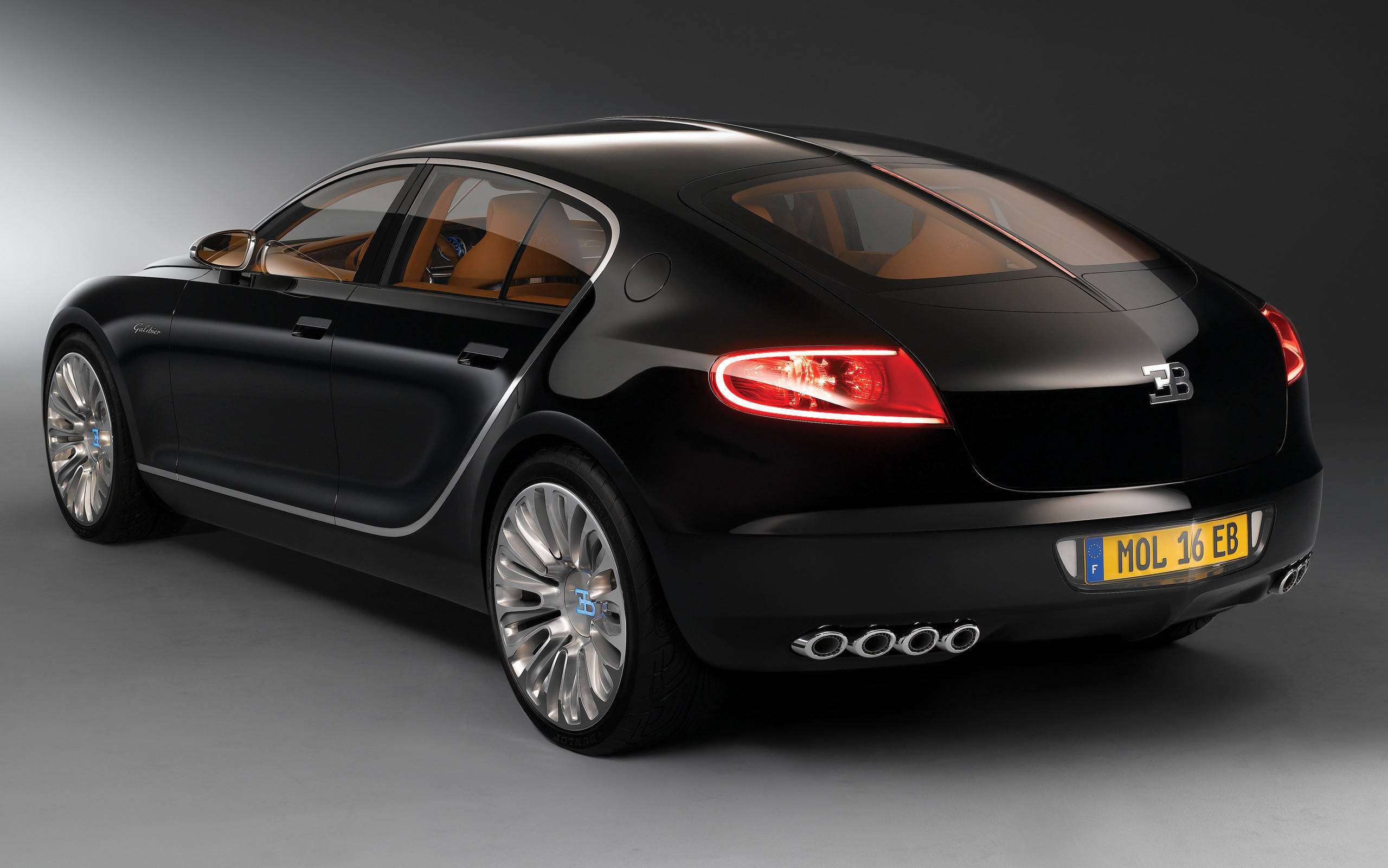 bugatti iPhone 桌布 壁紙 — 一輛時尚的黑色Bugatti Grand Sport Vitesse，在工作室燈光下展示，帶有發光的紅色尾燈和棕褐色皮革內飾。