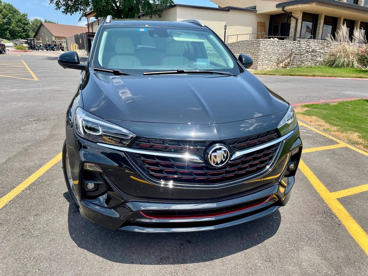 Buick 桌布 壁紙 — 一輛時尚的黑色Buick SUV停放在陽光明媚的停車場，背景有黃線和石建築。
