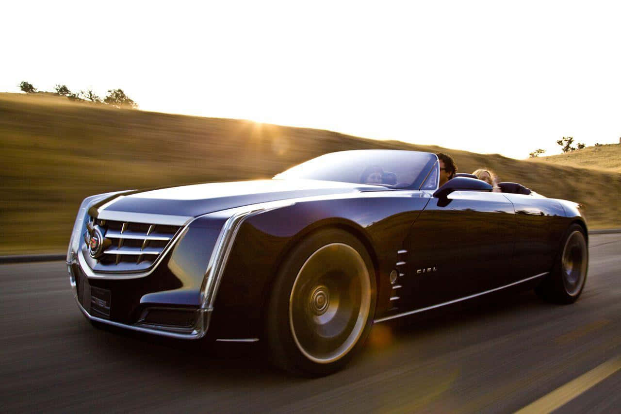 Cadillac 桌布 壁紙 — 一輛時尚的黑色Cadillac概念敞篷車在陽光明媚的高速公路上疾馳，背景是模糊的山丘。