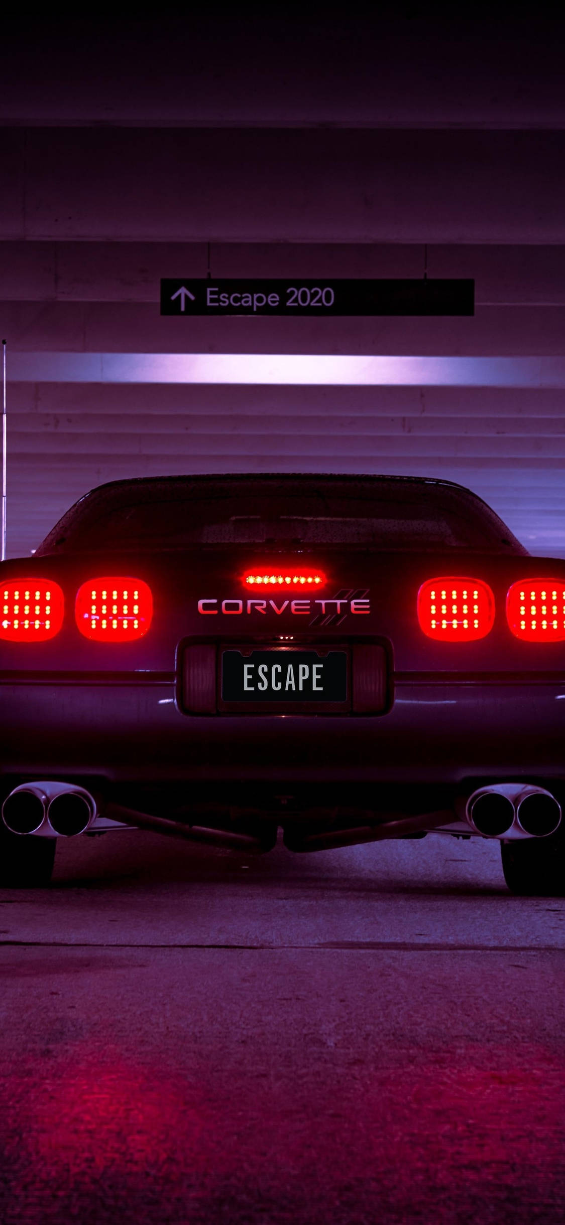 corvette 桌布 壁紙 — 一輛時尚的黑色Corvette，帶有發光的紅色尾燈，停在光線昏暗的車庫中，車庫上方有一個寫著Escape 2020的標誌。