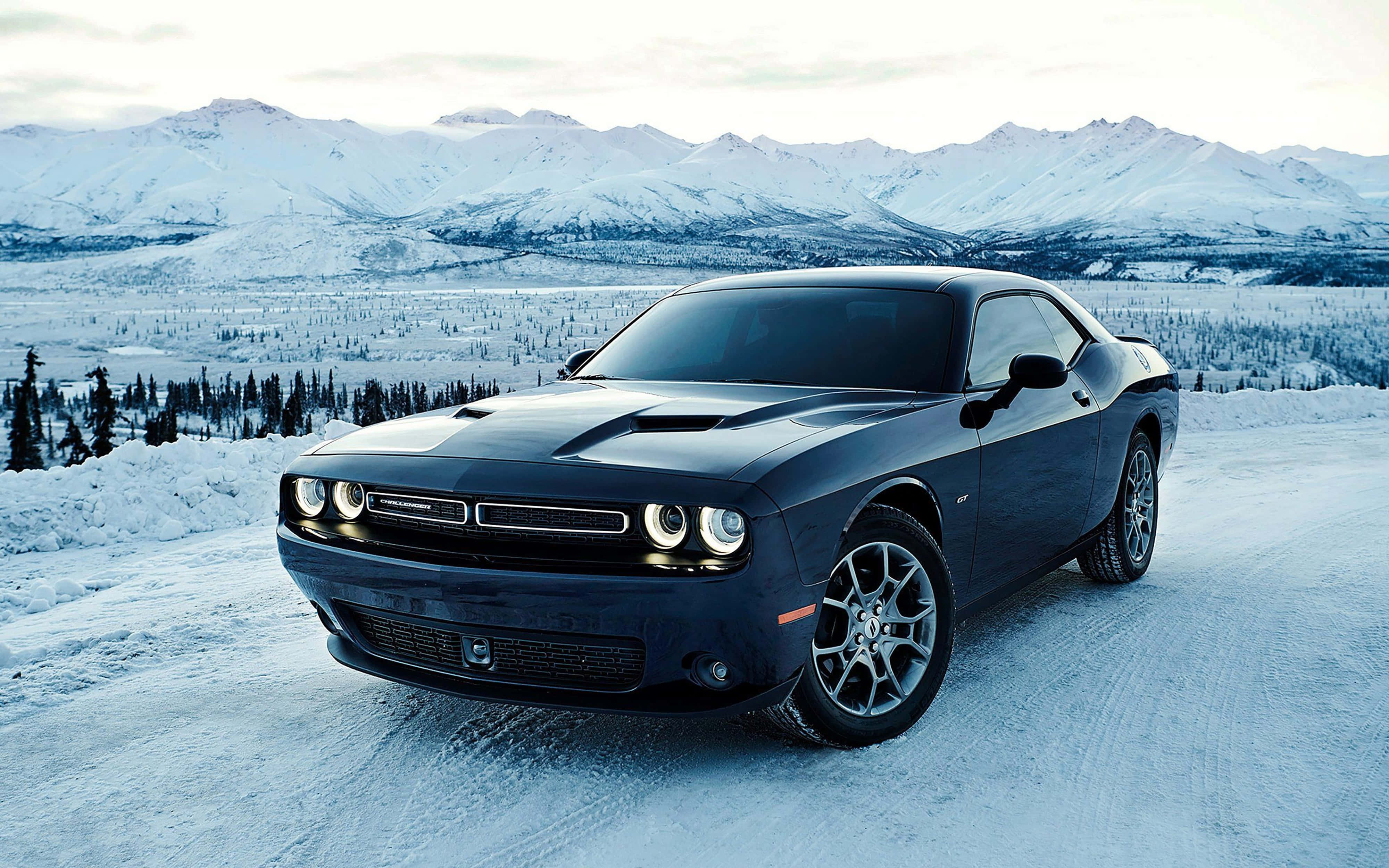 Dodge 桌布 壁紙 — 一輛時尚的黑色Dodge Challenger停放在積雪的道路上，背景是白雪覆蓋的山脈。