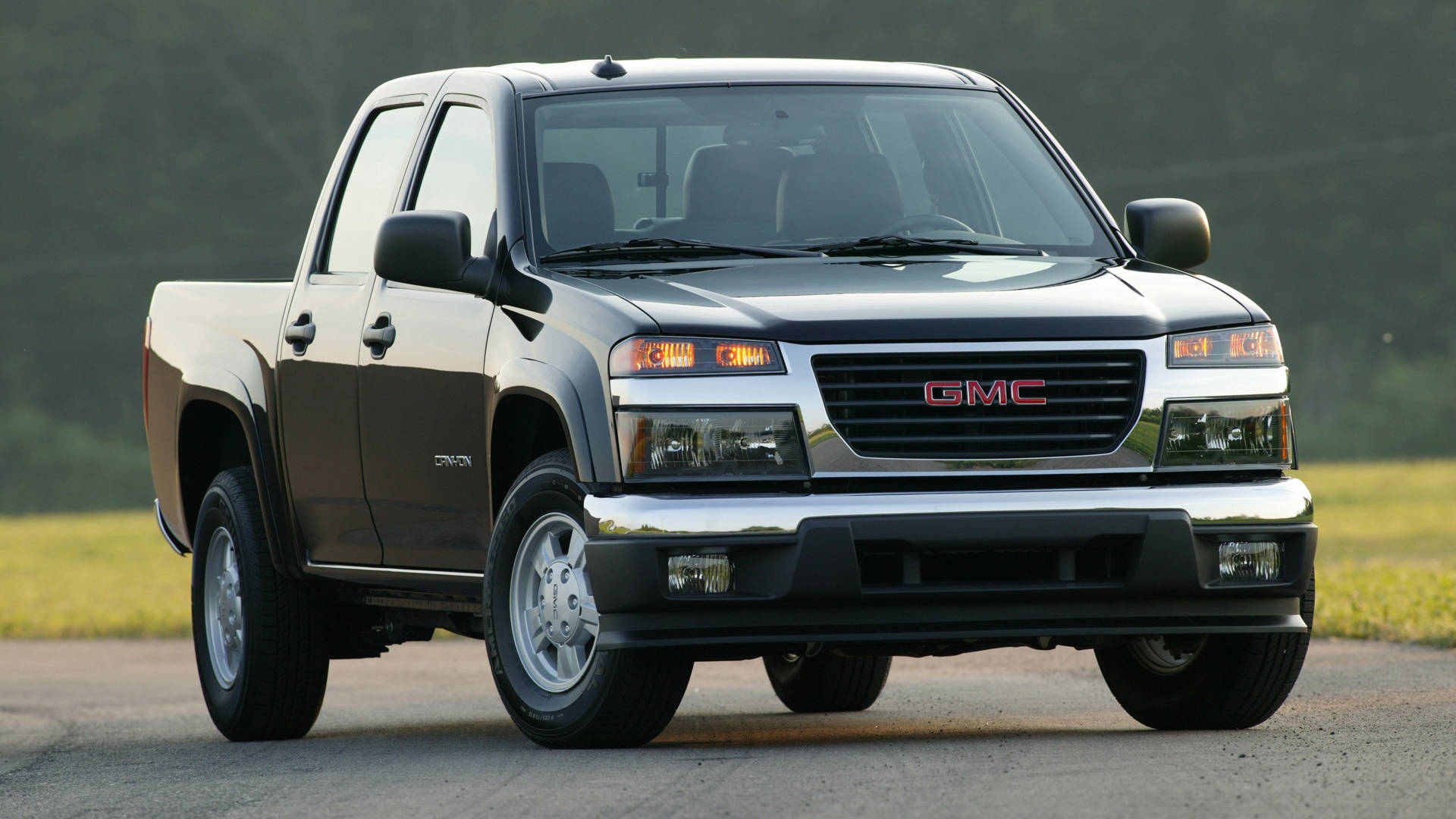 Gmc 桌布 壁紙 — 一輛時尚的黑色GMC Canyon皮卡車停在鋪砌的道路上，背景是草地和樹木。